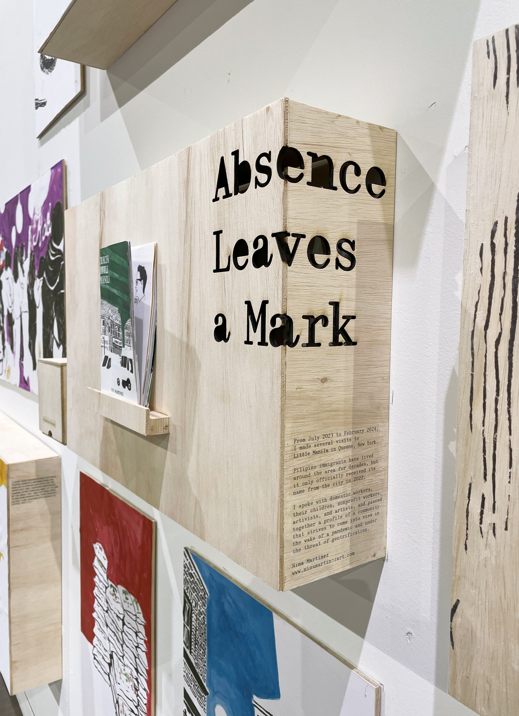 A detail shot of the corner of the plywood display, showing the thesis title Absence Leaves a Mark, plus a short description of my project created with gel transfer.