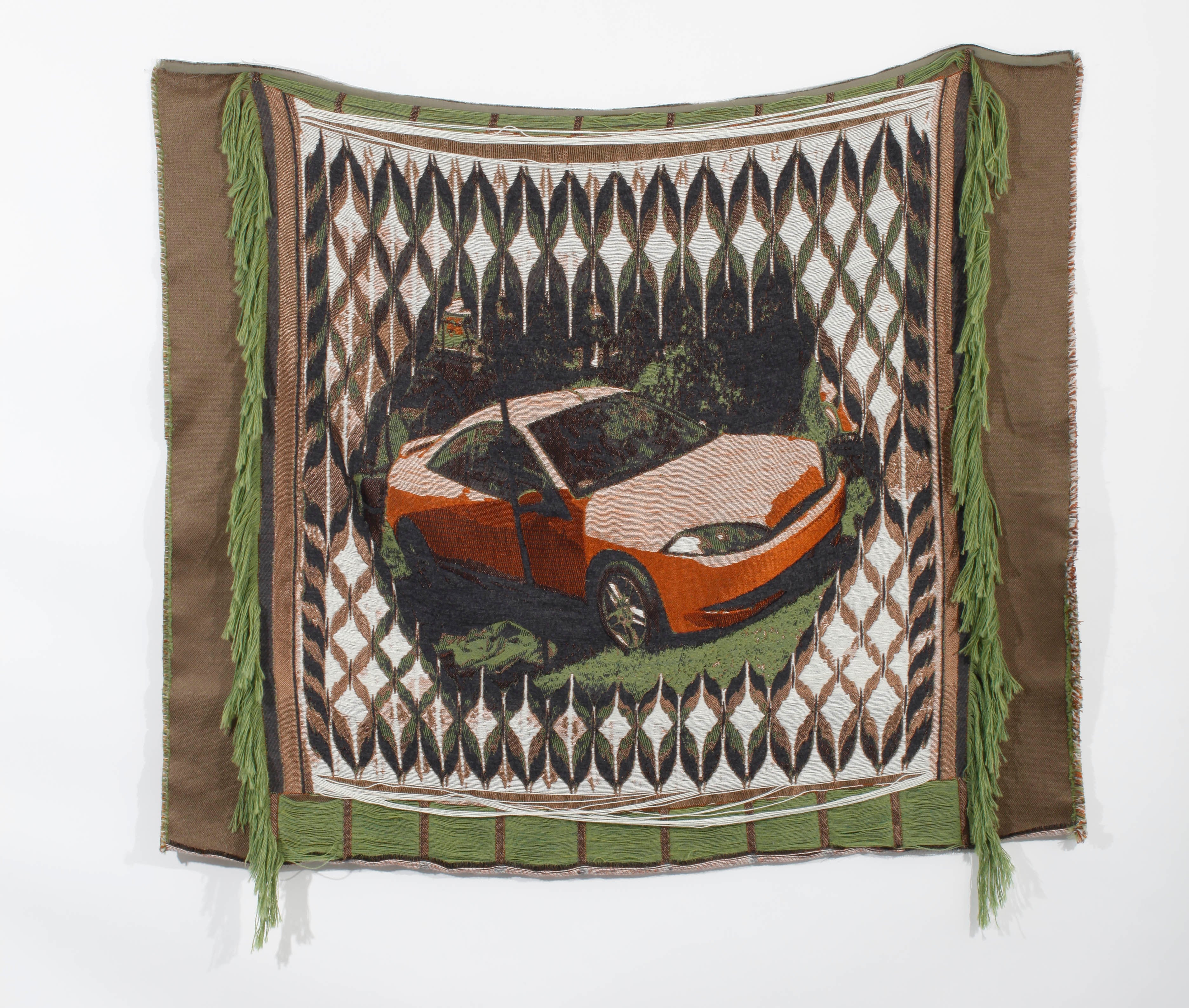 /A%20medium%20sized%20square%20weaving%20depicting%20an%20orange%20car%20in%20the%20middle%20with%20a%20black%20and%20white%20pattern%20around%20it%20hanging%20on%20a%20white%20wall.