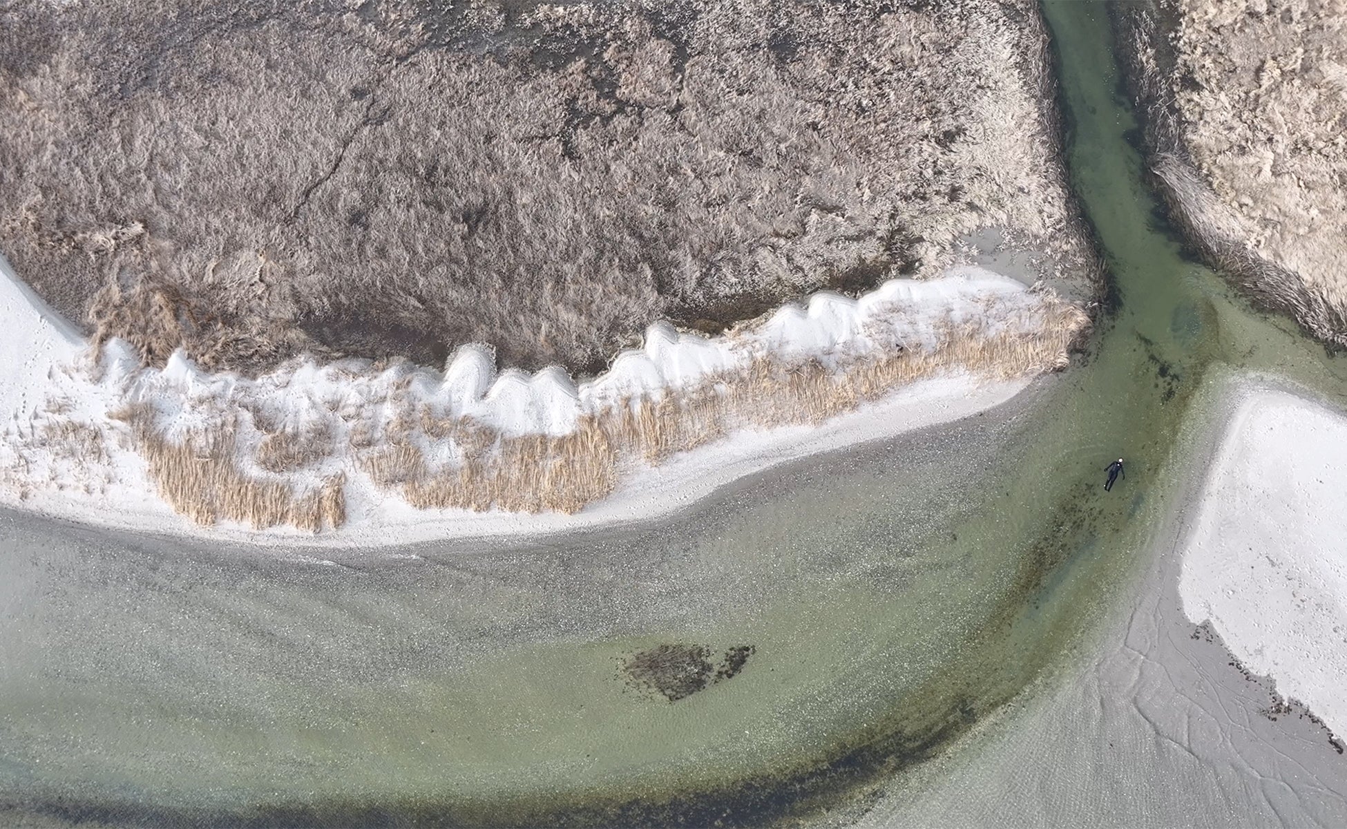 /Drone%20footage%20of%20a%20person%20floating%20in%20the%20mouth%20of%20a%20salt%20marsh%20channel.
