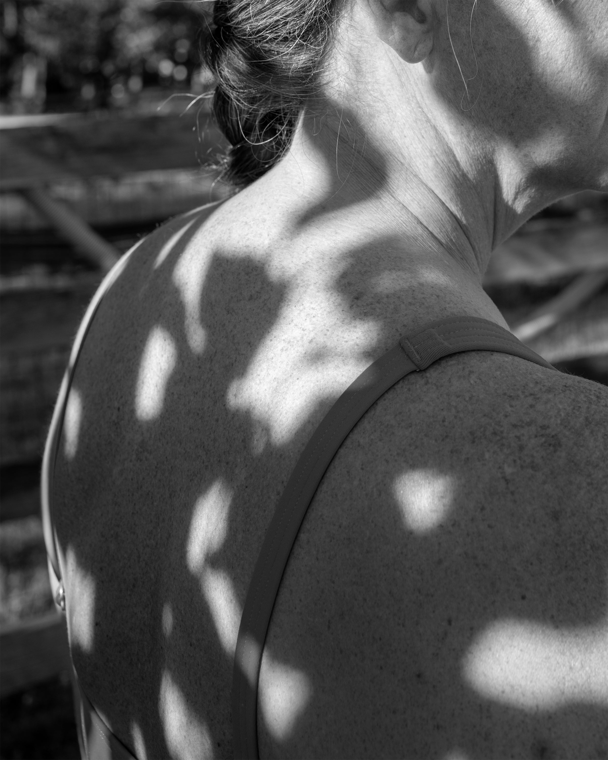 /shadows%20from%20a%20nearby%20tree%20projected%20onto%20the%20back%20of%20a%20woman%20in%20her%20mid-50%27s.
