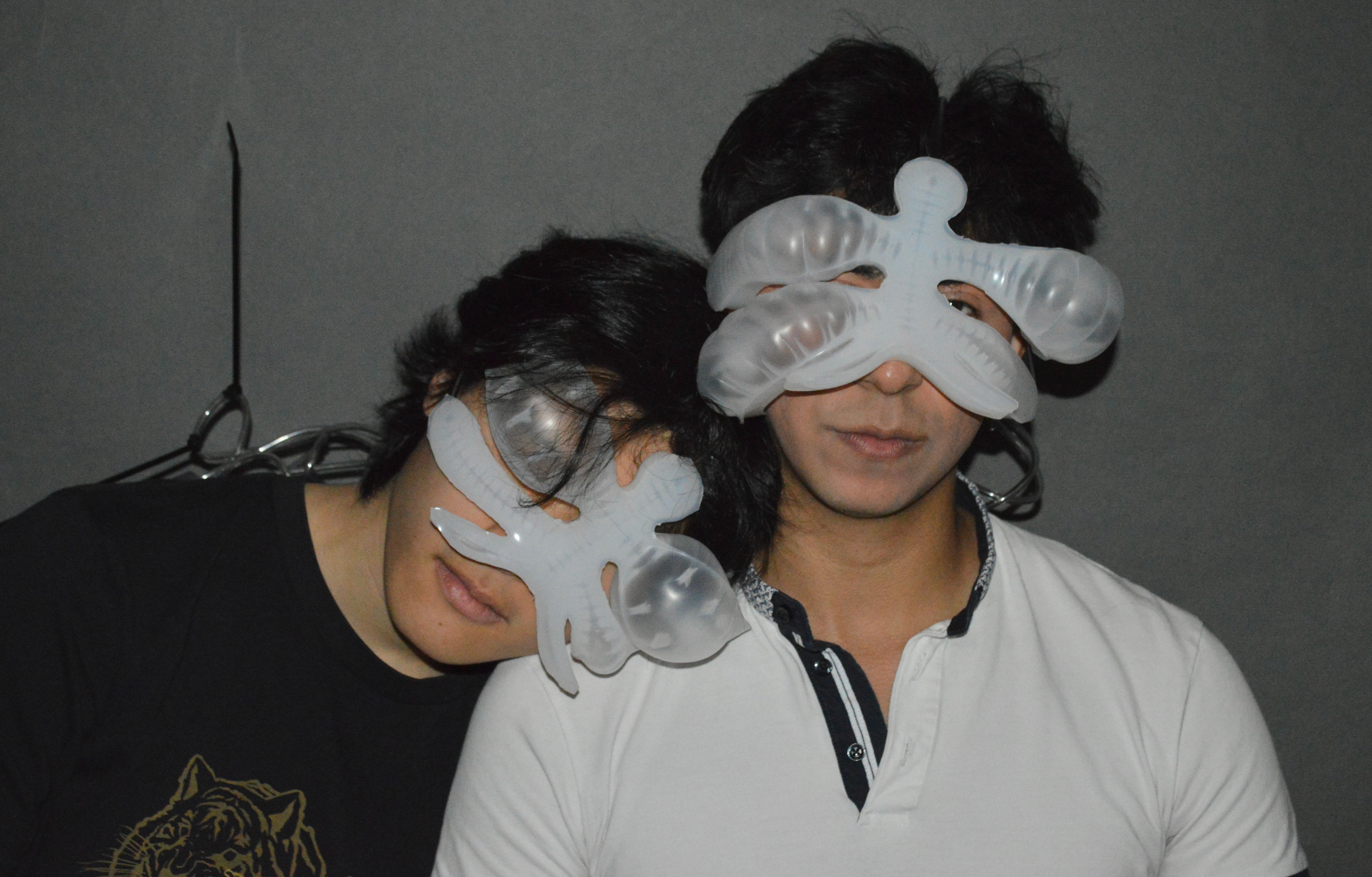 Dylan and Brandon, one leaning on the other's shoulder, adorning chimera, a soft robotic entity that sits on the face. The augmentation is inflated reflecting their emotion.