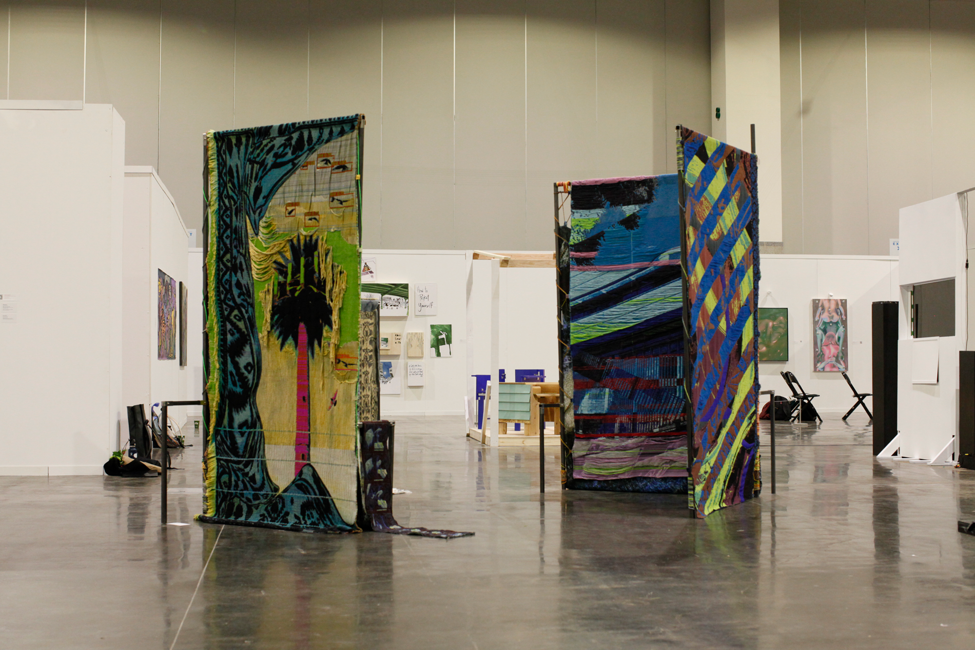 Large scale installation of metal steel frames with colorfull weavings standing in the middle of the floor at the convention center.