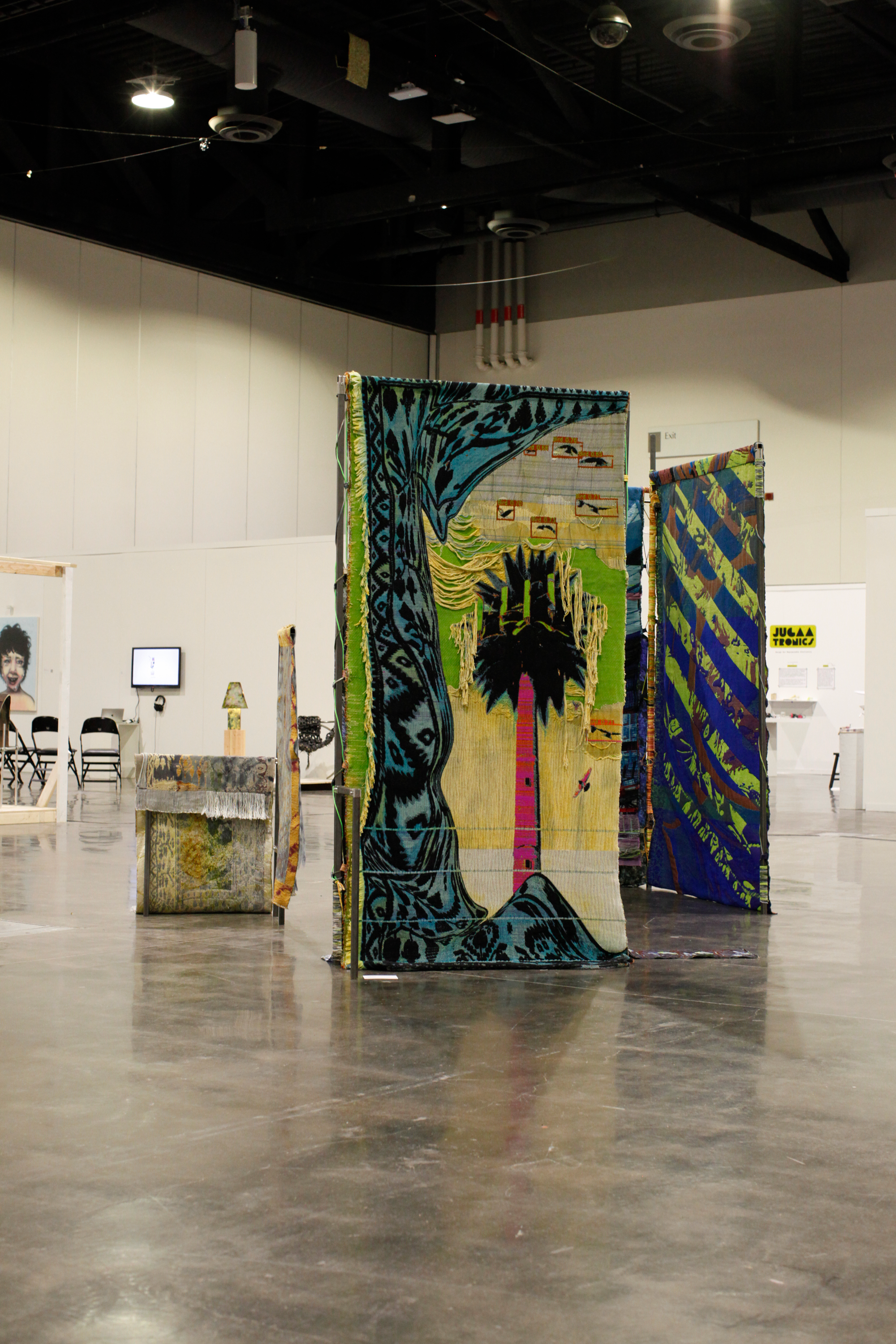 Large scale installation of metal steel frames with colorfull weavings standing in the middle of the floor at the convention center.