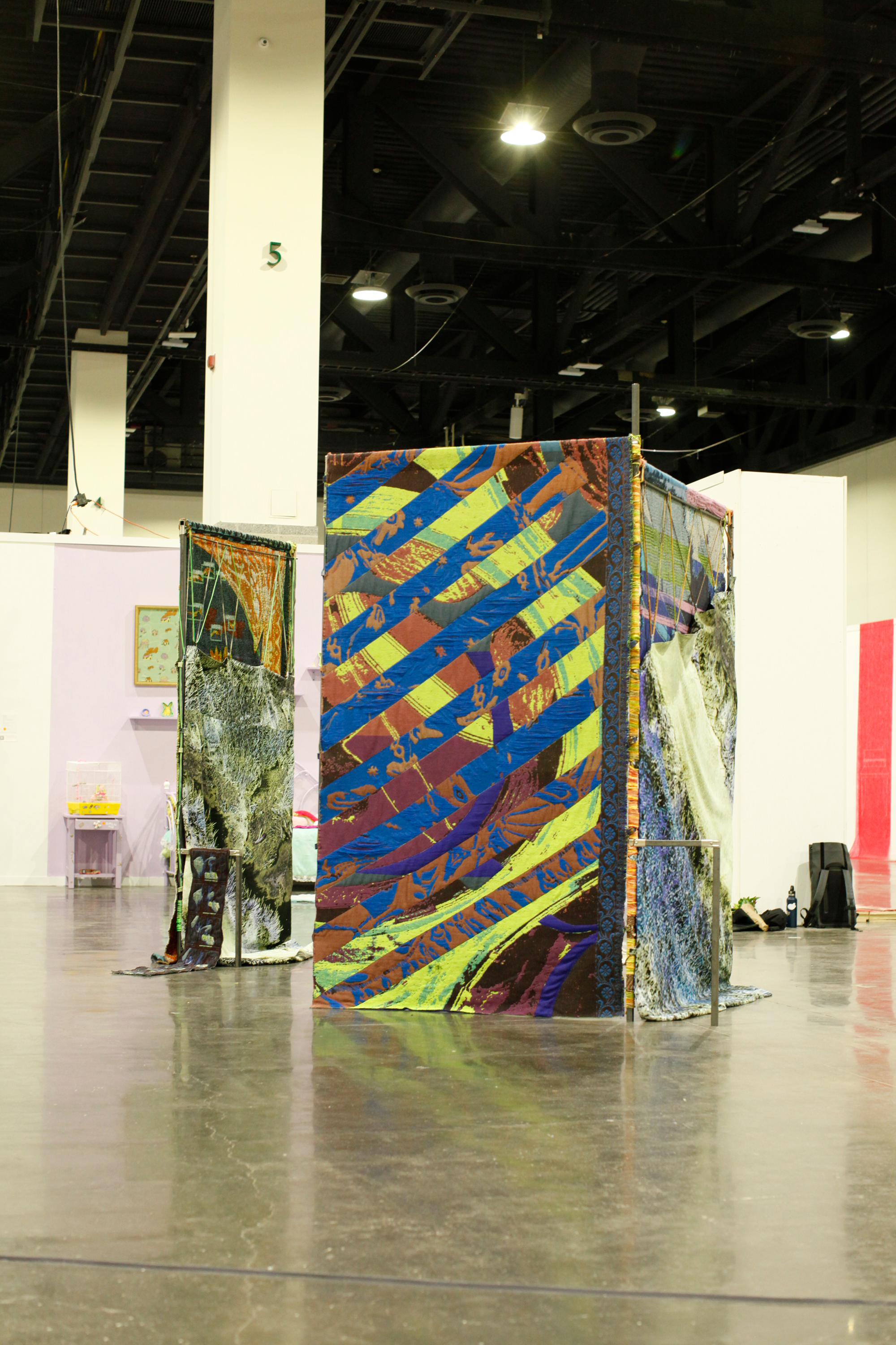 Large scale installation of metal steel frames with colorfull weavings standing in the middle of the floor at the convention center.