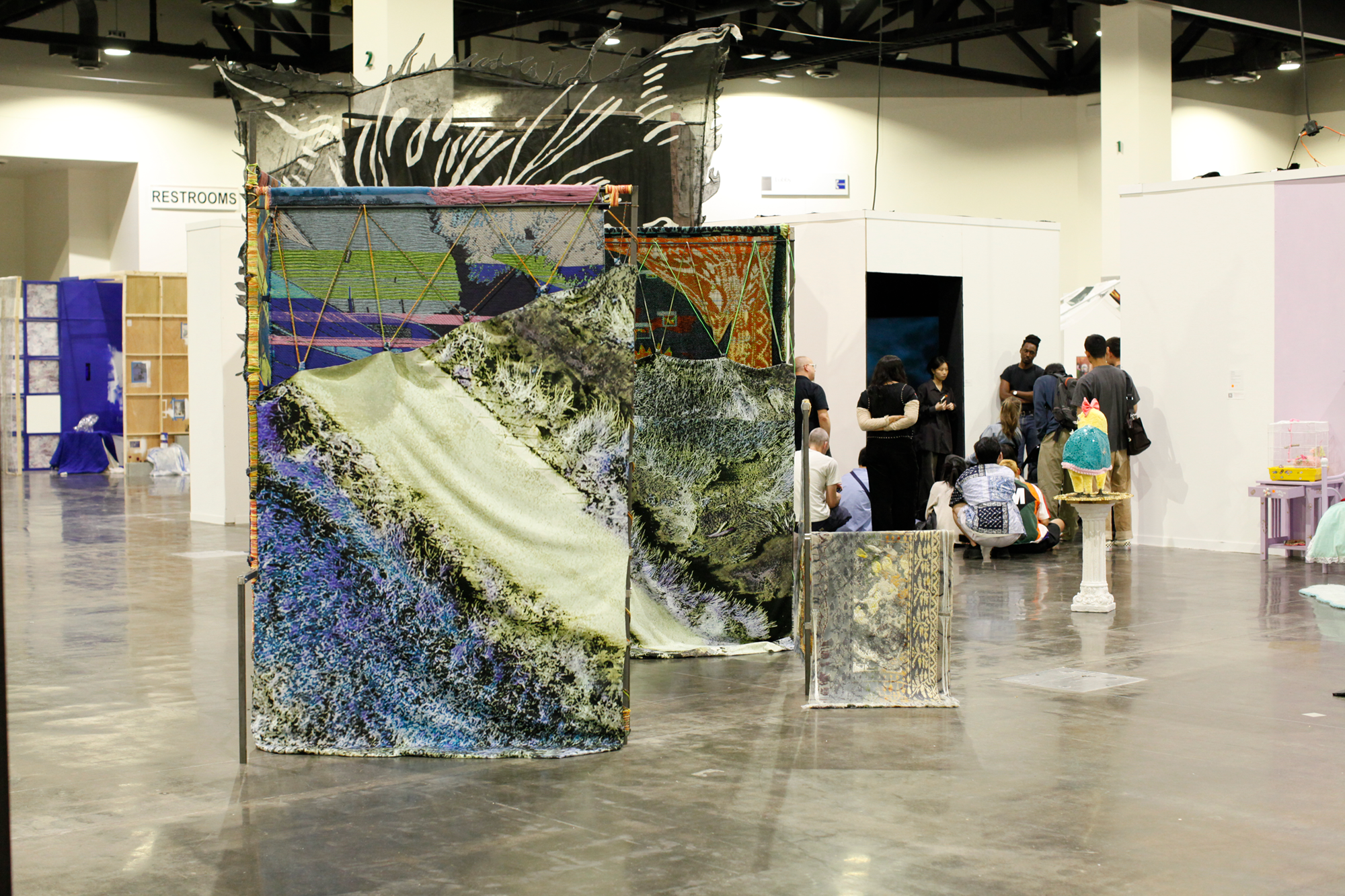 Large scale installation of metal steel frames with colorfull weavings standing in the middle of the floor at the convention center.
