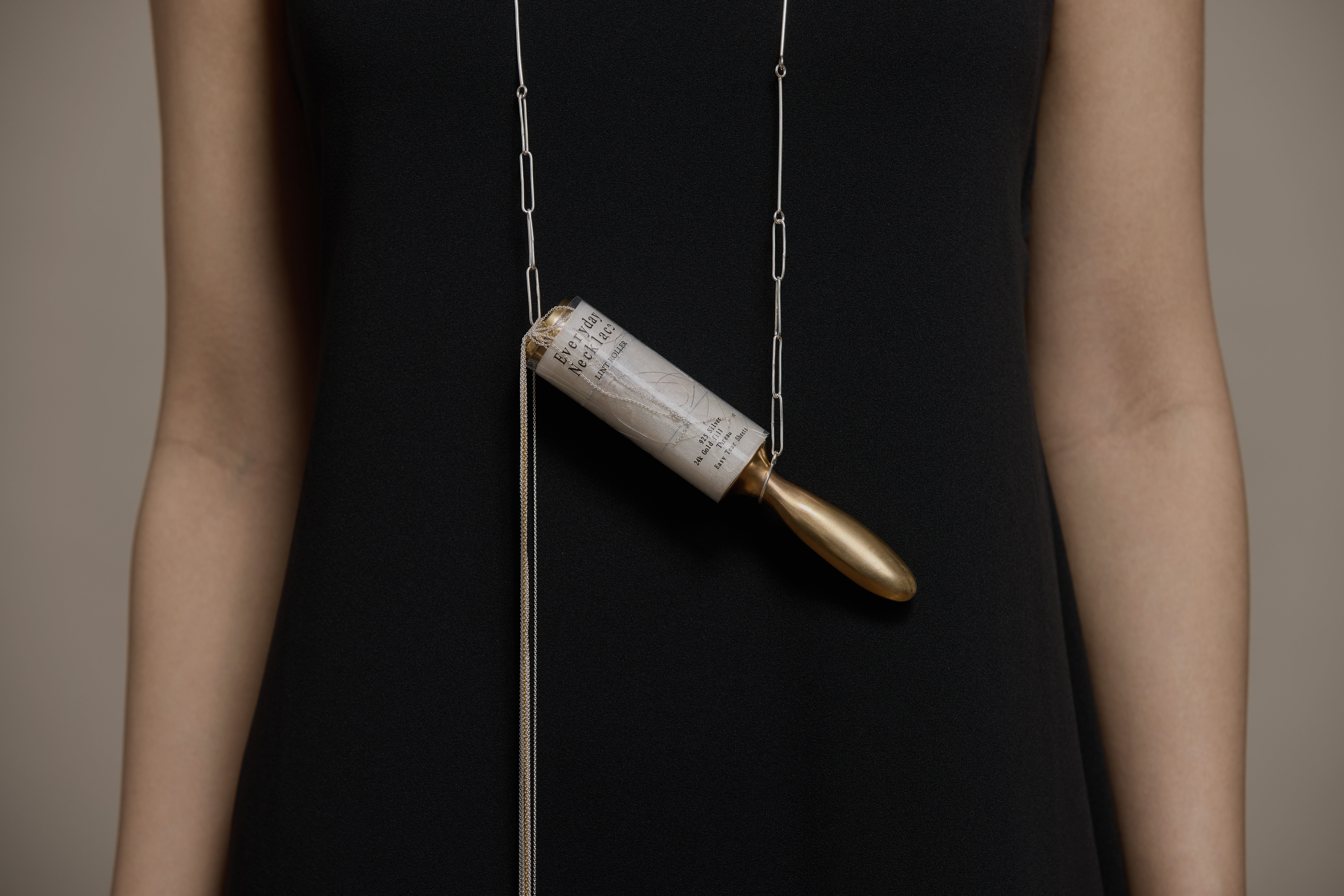 Necklace with metal lint roller pendant; segments tear off as individual pieces, titled and packaged “Everyday Necklace.” 