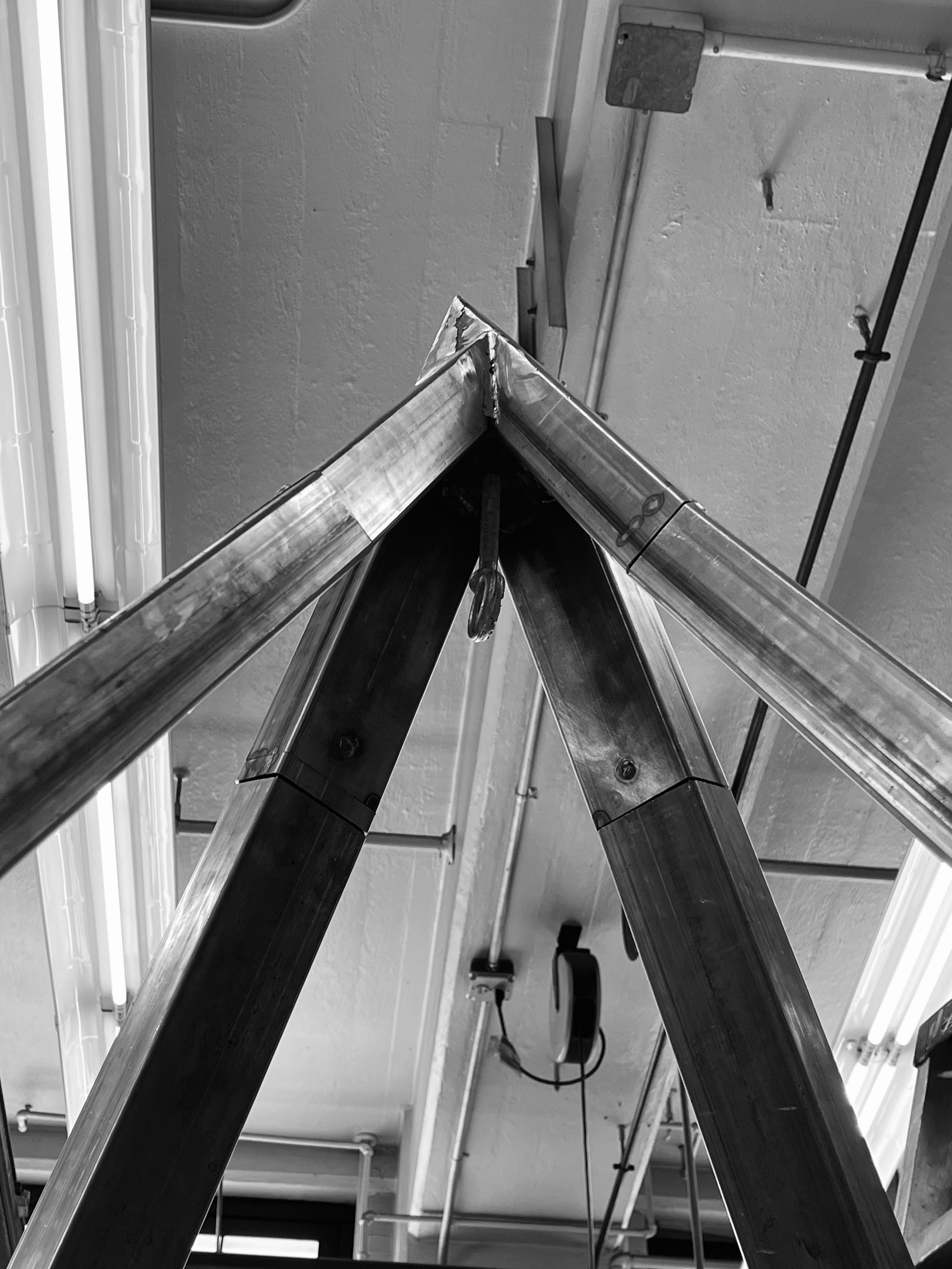 The apex of a pyramid shaped steel structure, with a forged eyebolt welded at the center 