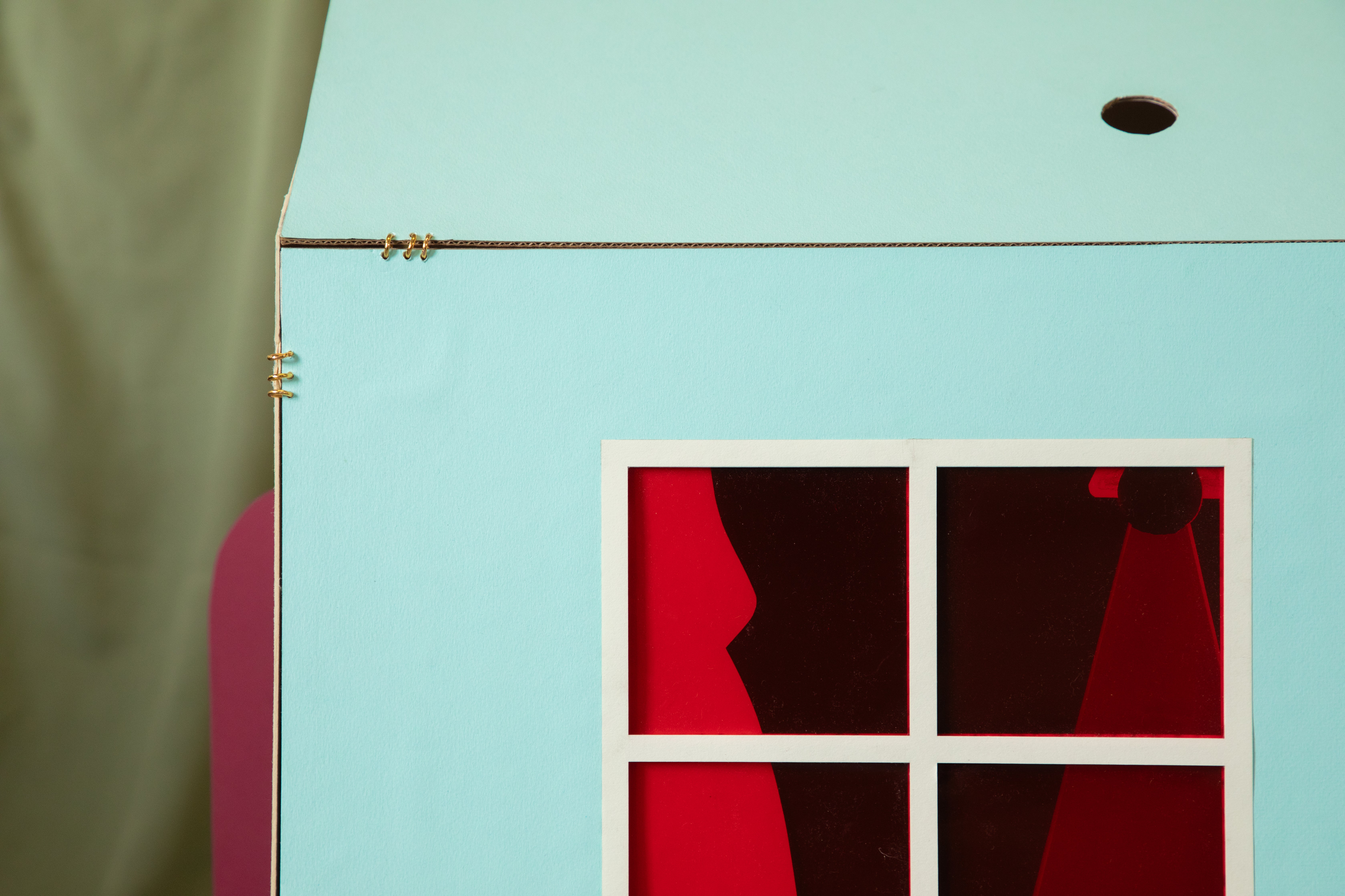 View of the facade of a house form depicting the day time sky with a window in red transparent material. 