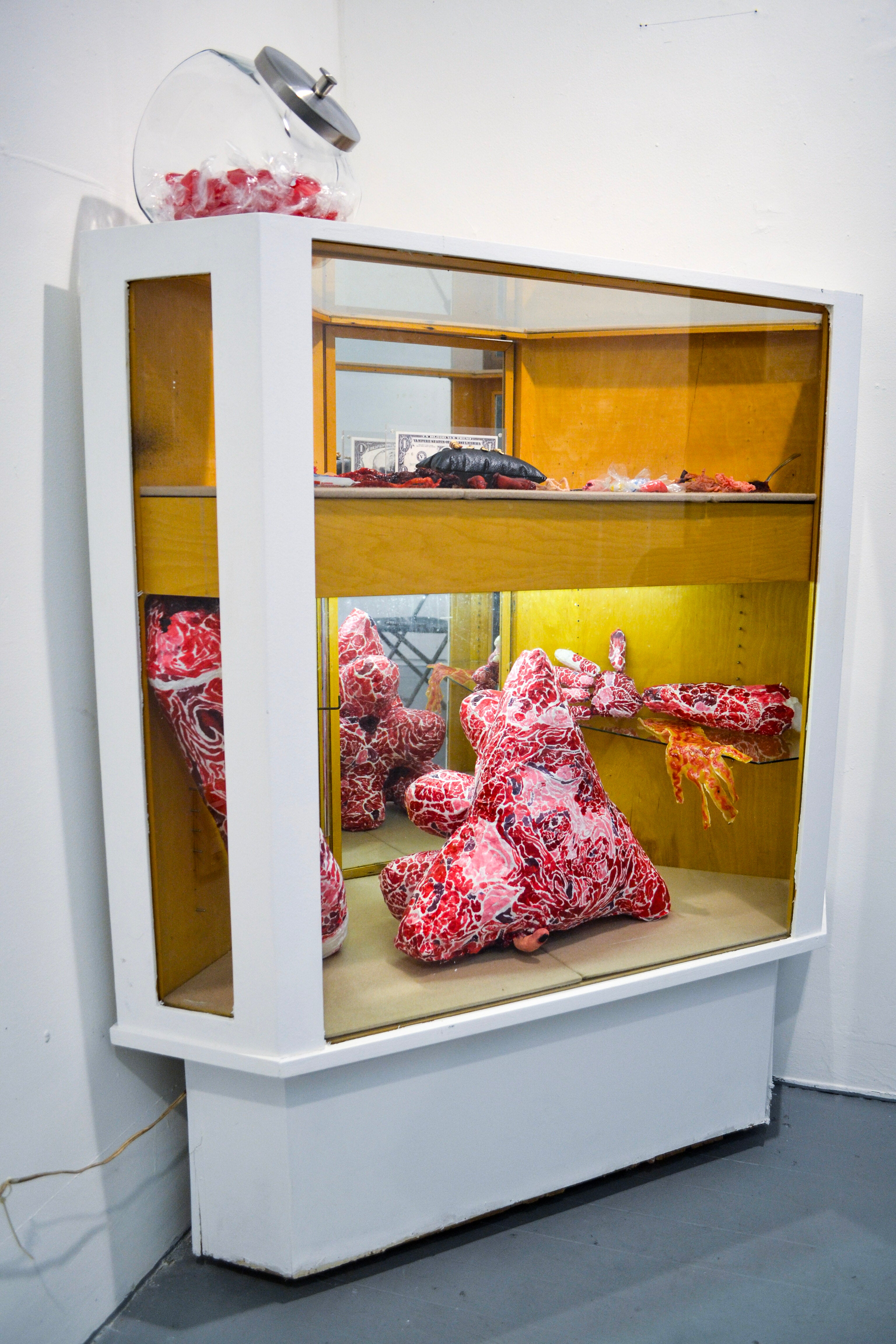 A corner jewelry display case with a variety of unusual items, including fake severed fingers and latex bloody sculptures. 