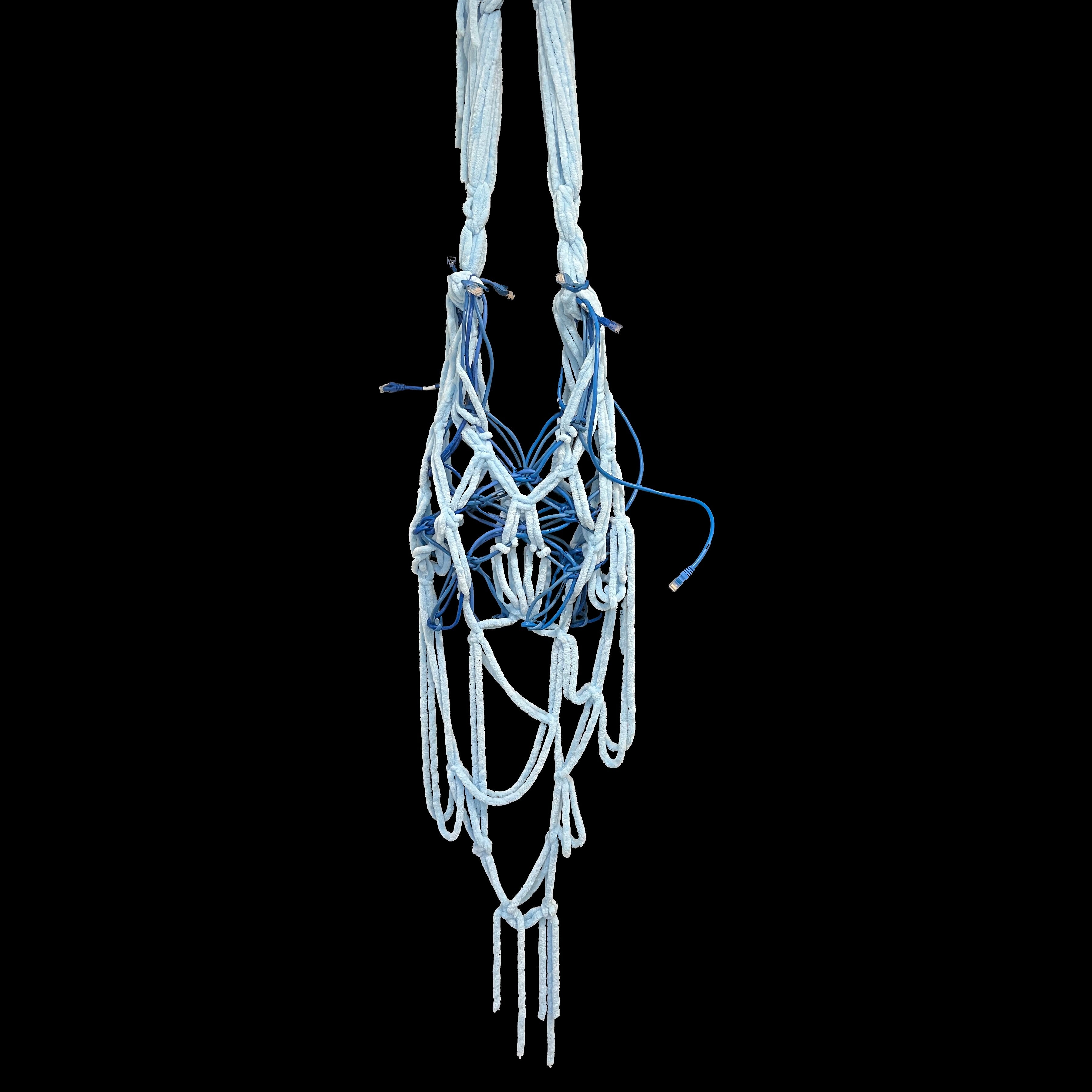 Hanging woven carrier bag made from blue fuzzy yarn and ethernet cables against a black background. Long looping strands and exposed cable ends contrast soft textile craft with rigid digital wiring, evoking entanglements between memory, technology, and physical objects.