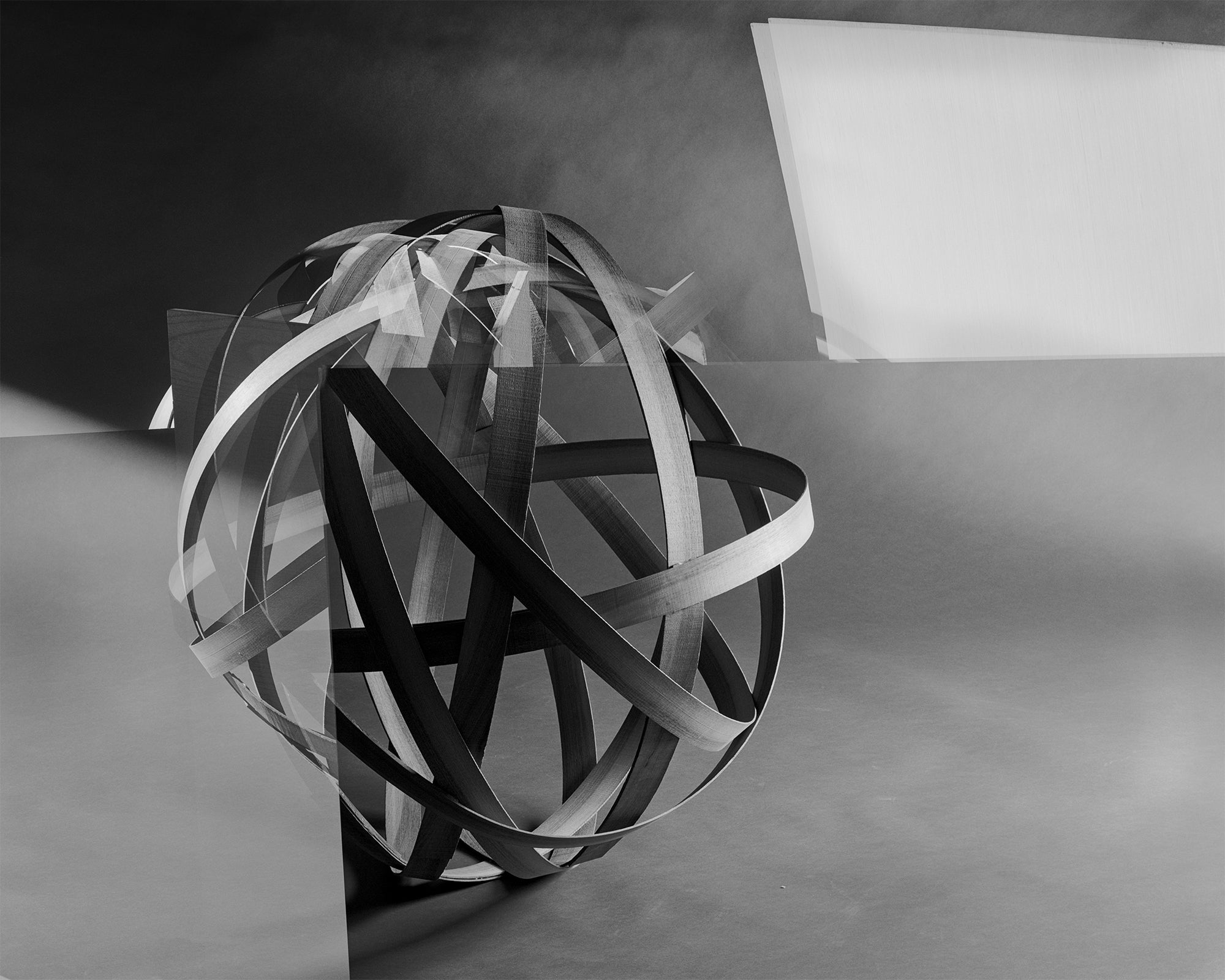 A photograph of bent wood made to look like a globe. 