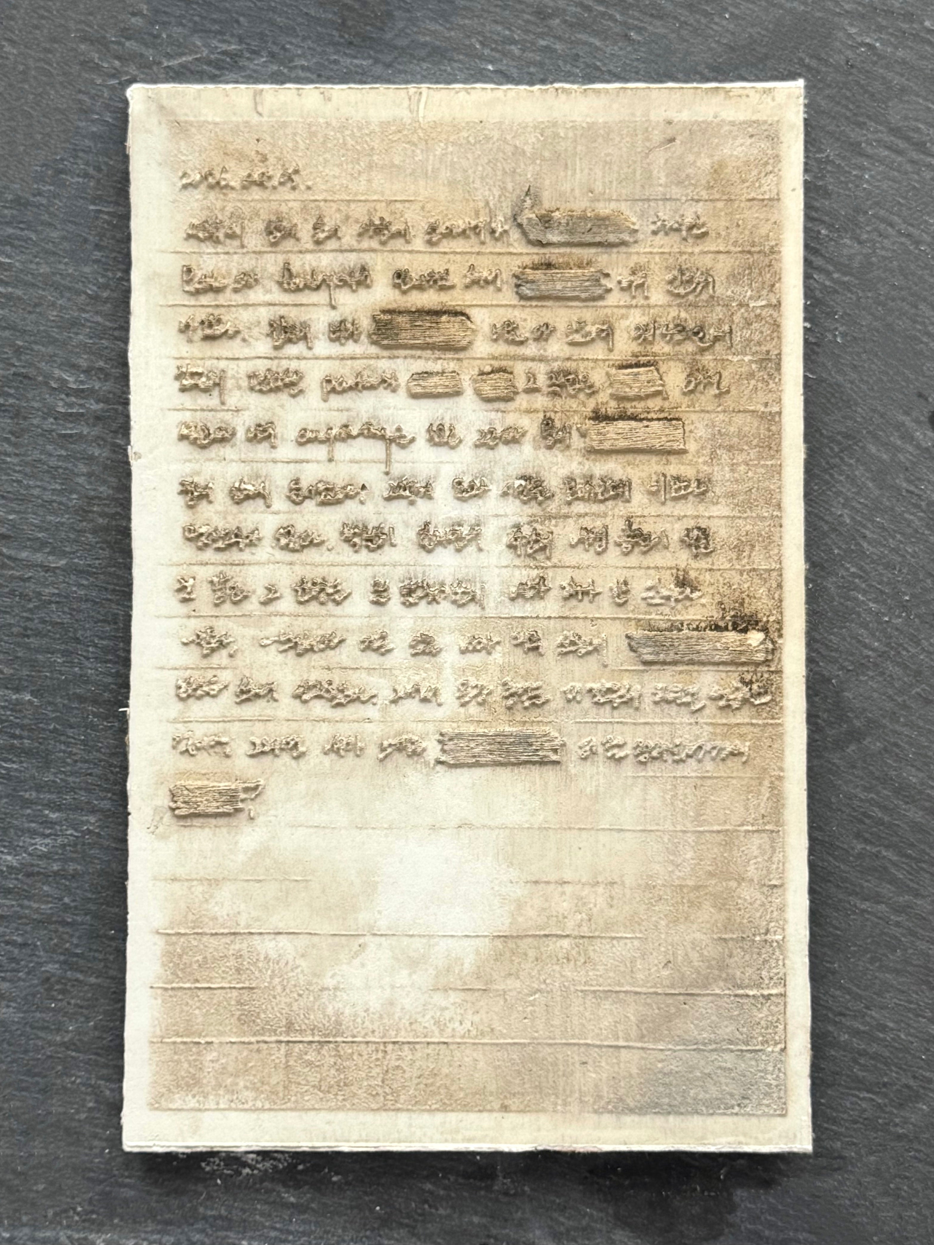 Close-up of a plaster page with raised handwritten text and redacted sections on a dark surface.
