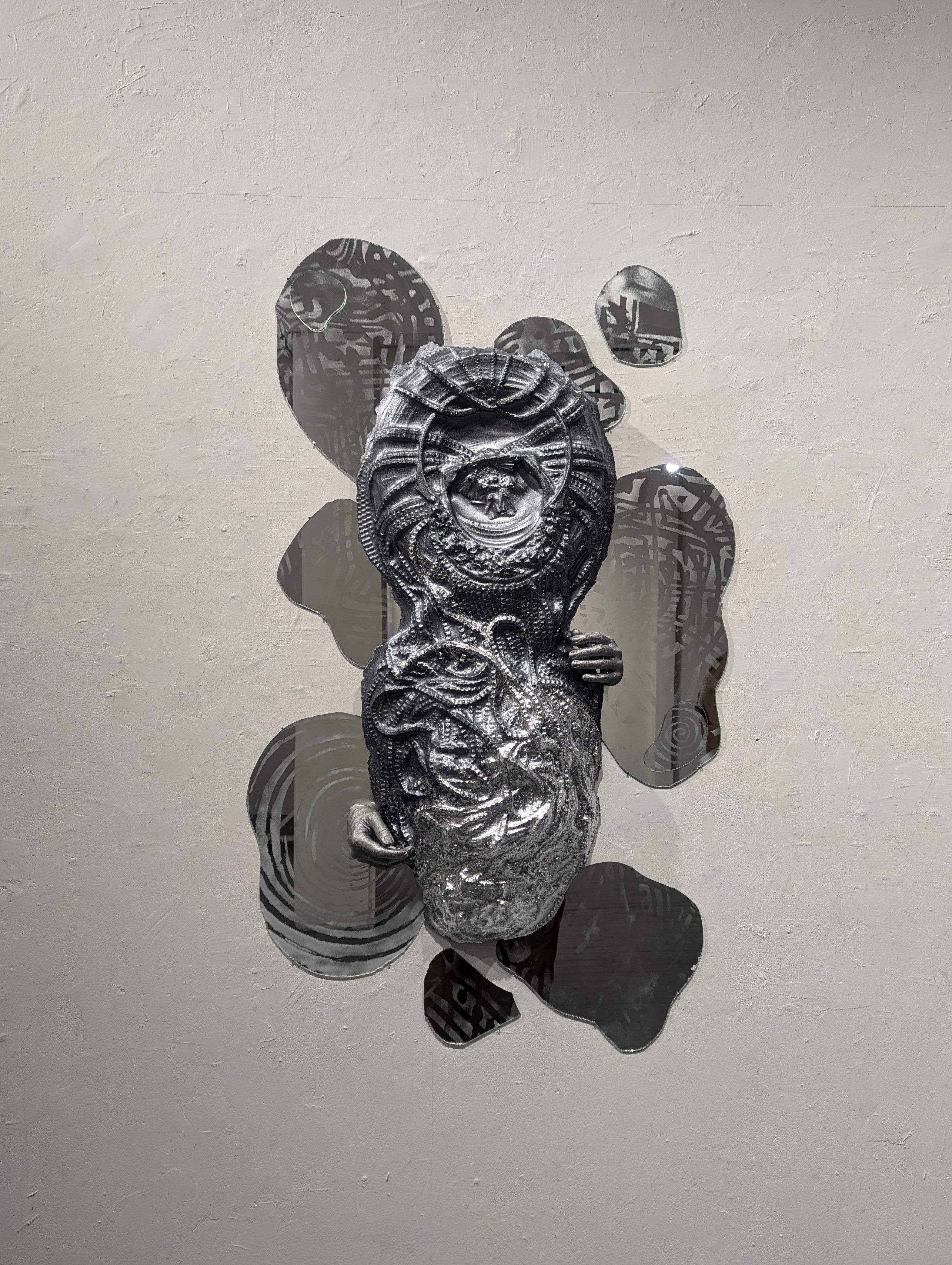 Dried bamboo and metal sculptures with tiny lights hang over a baby banana tree, casting refracted light in a dark room.