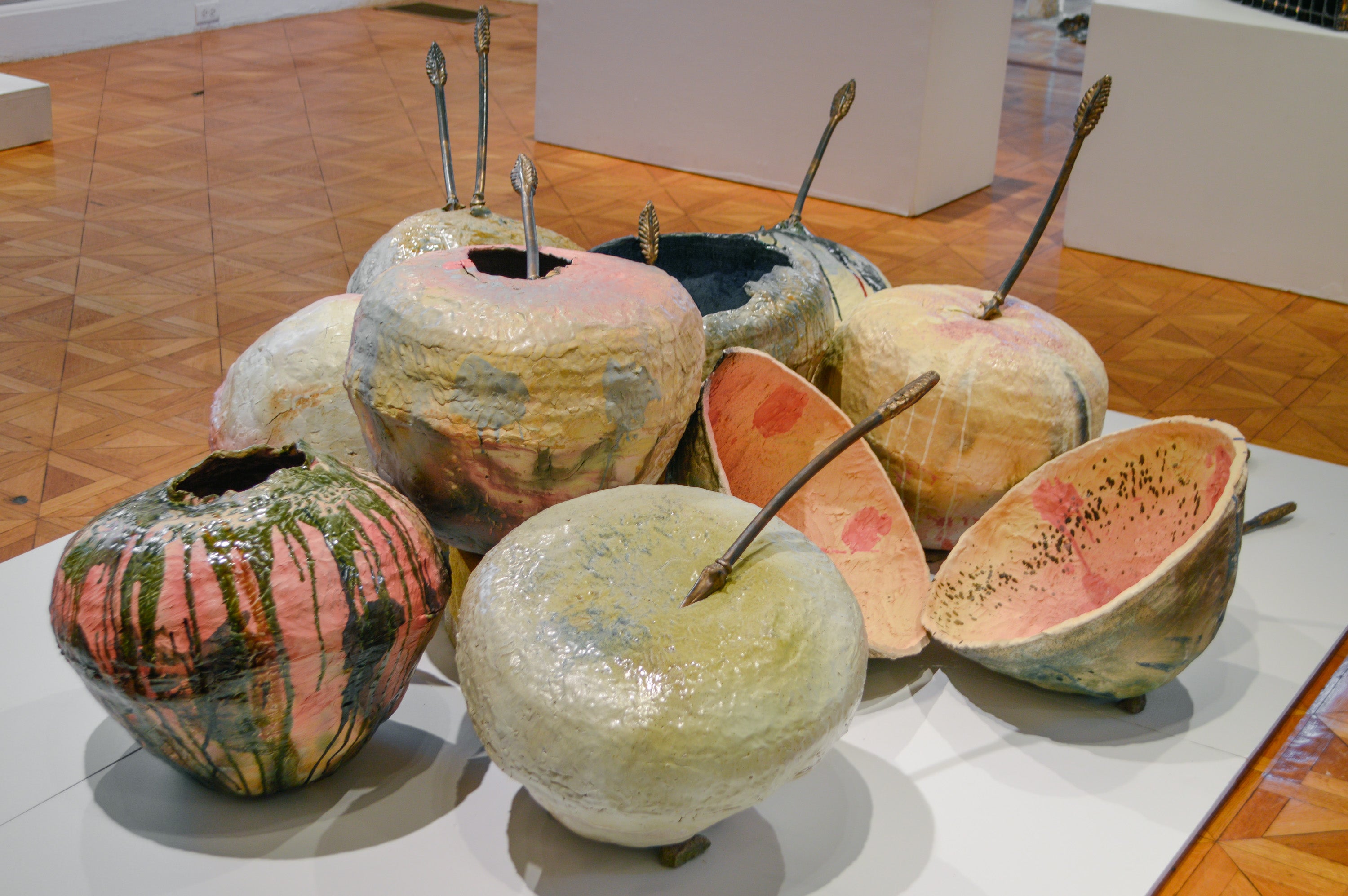 Ten multicolored ceramic spheres in a pile. Eight bronze-colored arrows protrude from the spheres. 