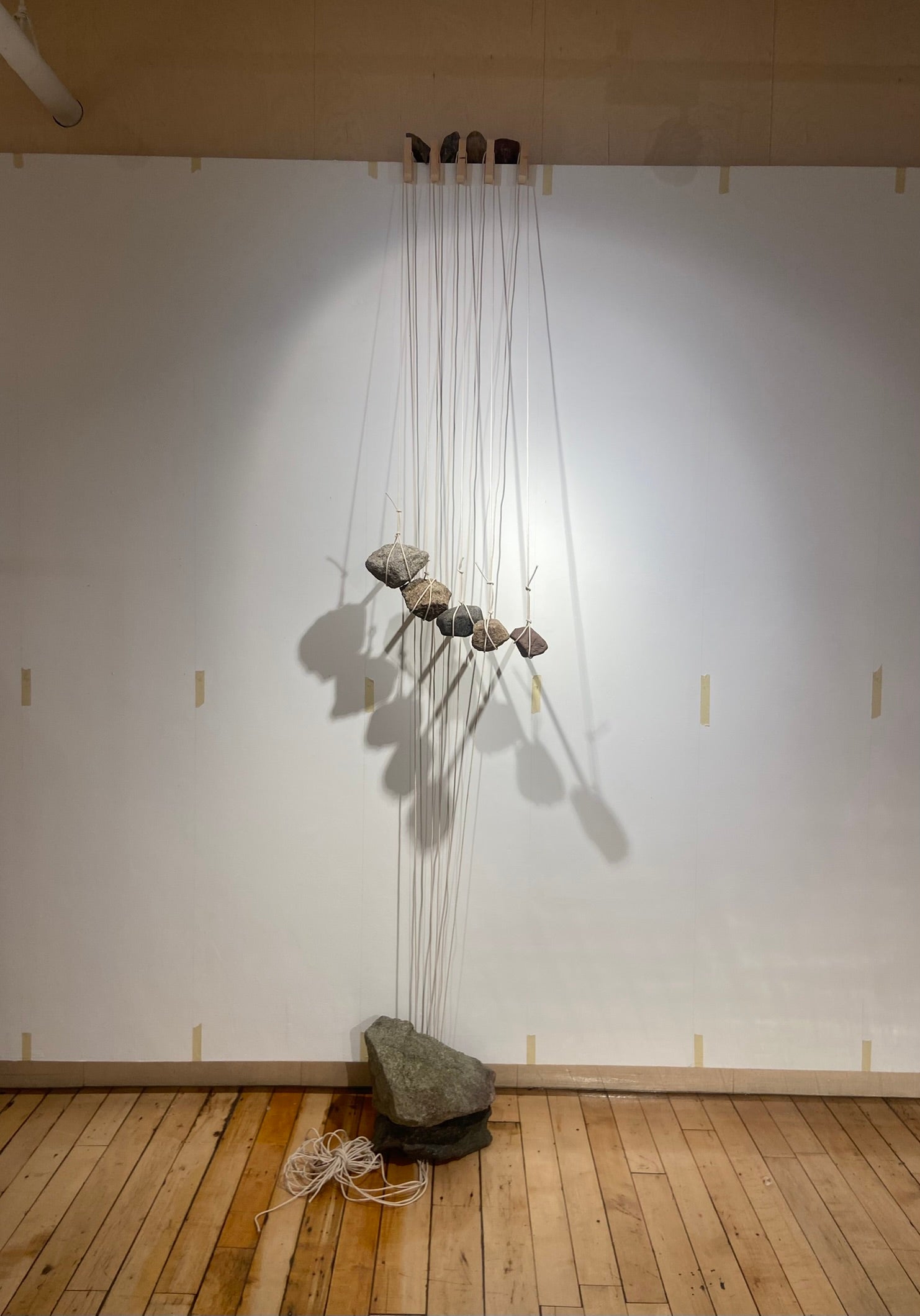 A massive anchor, bracing stones at the top, and hanging rocks are attached with string and hold wood beams in place without fasteners.