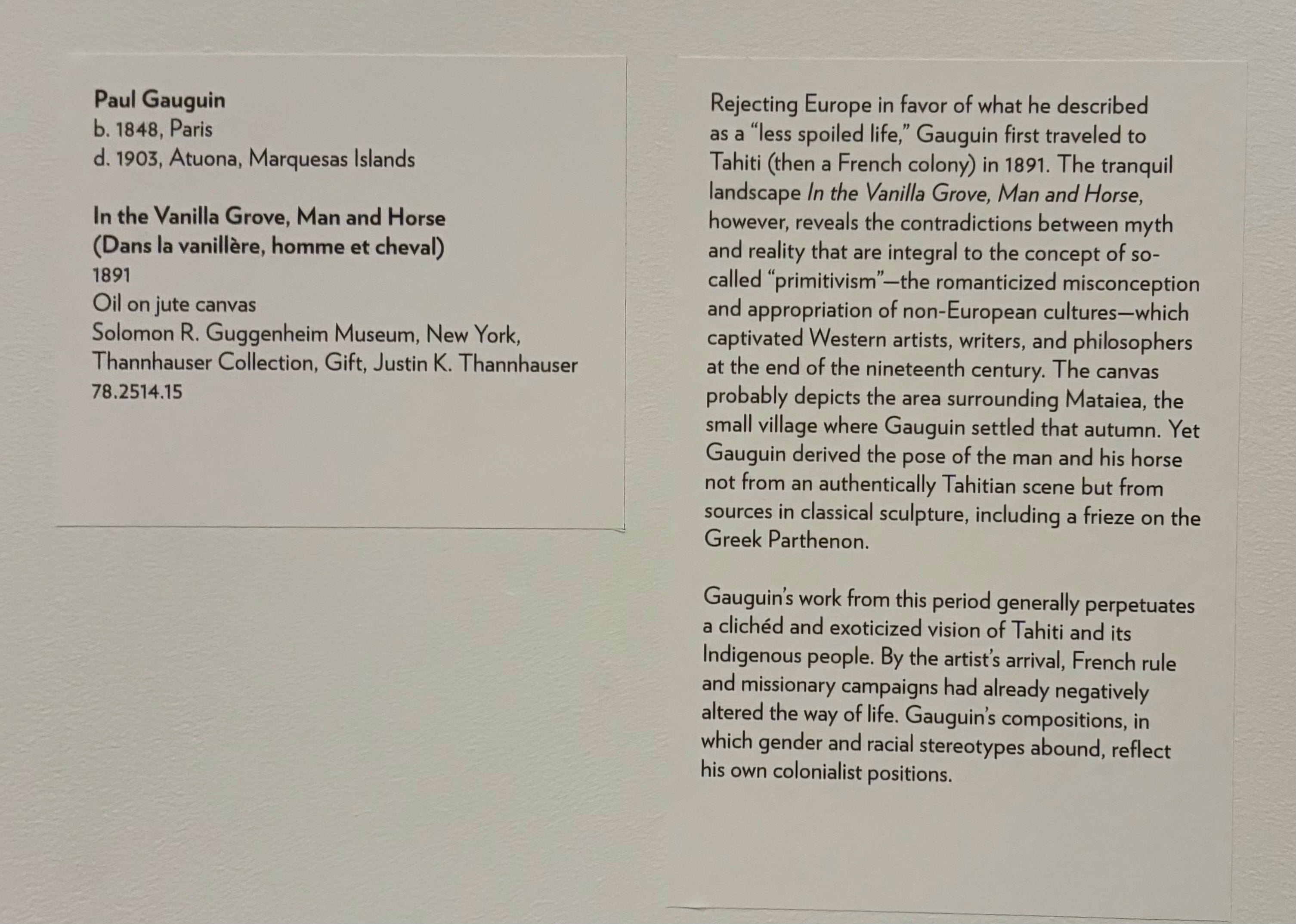 Two rectangular labels affixed to a white wall. The left label lists the artist's name, biographical information, and collection details about the painting. The right label shares a brief interpretive description of Gauguin's travels to Tahiti and exoticizing portrayal of its Indigenous people. 