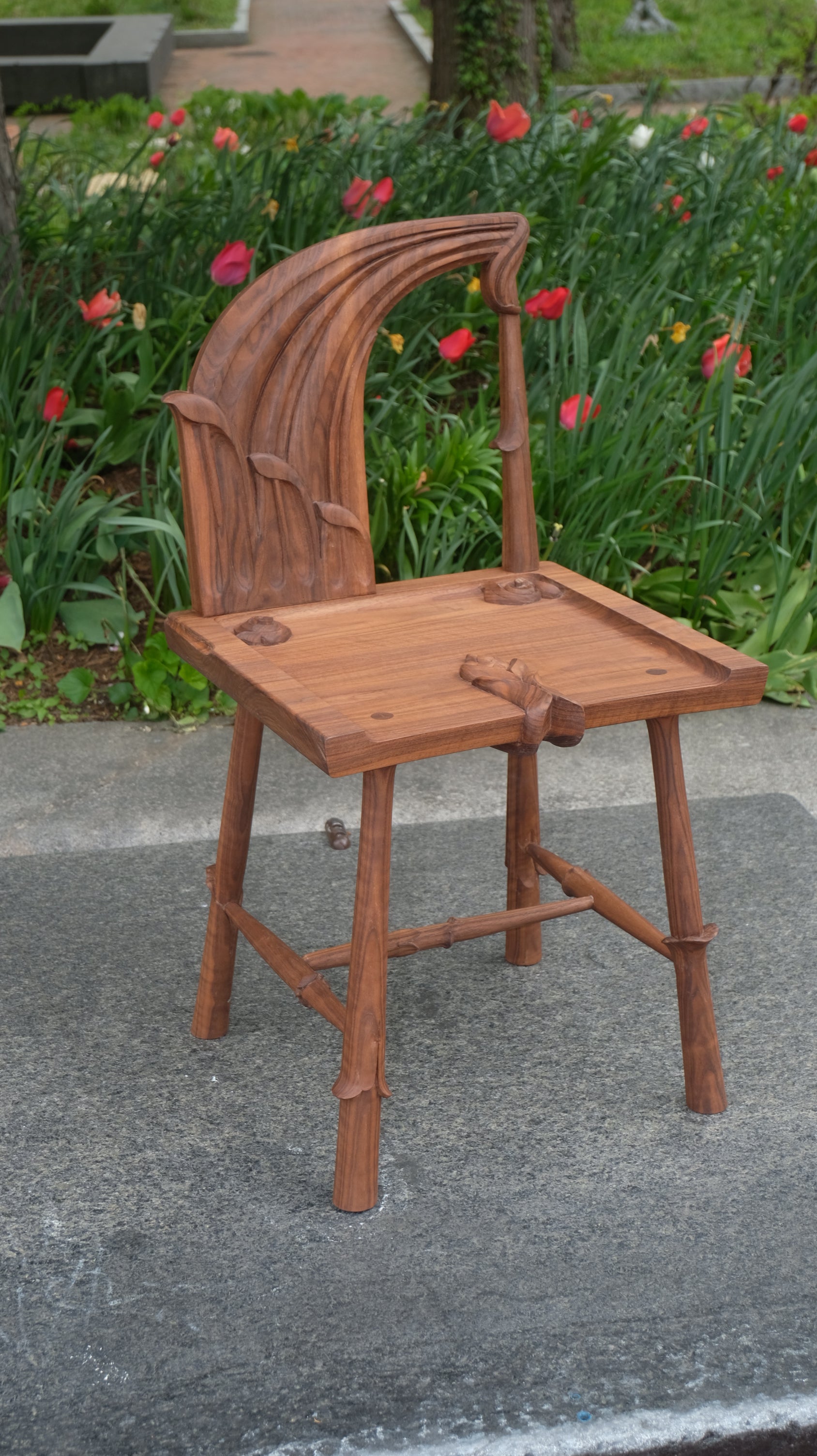 Wooden spindle back chair with curved seat and vertical spindles, 28 inches tall, merging traditional joinery with contemporary organic form.
