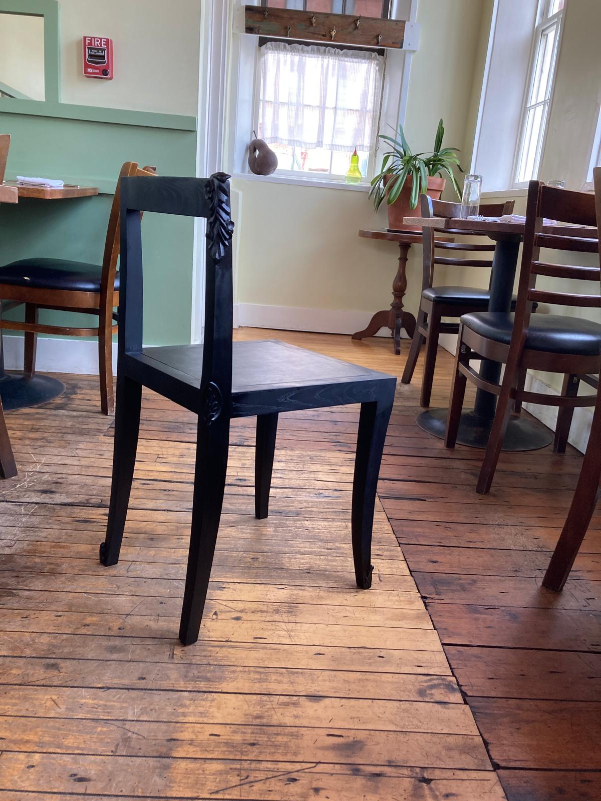 Hand-carved dining chair with clean lines, leather seat, and varying leaf motifs reflecting restaurant’s seasonal food theme.