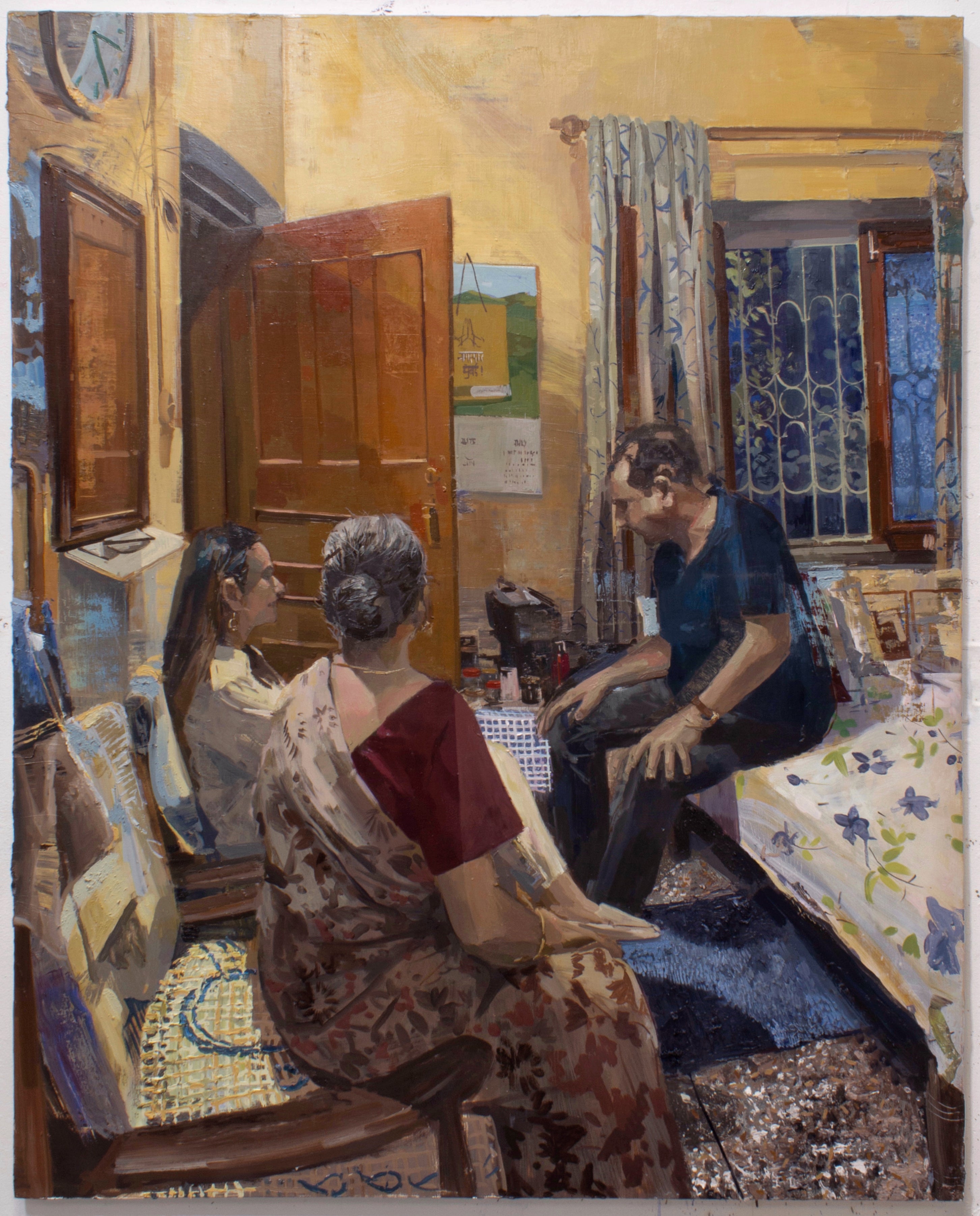 Three figures seated in a room lit with a warm yellow light. 