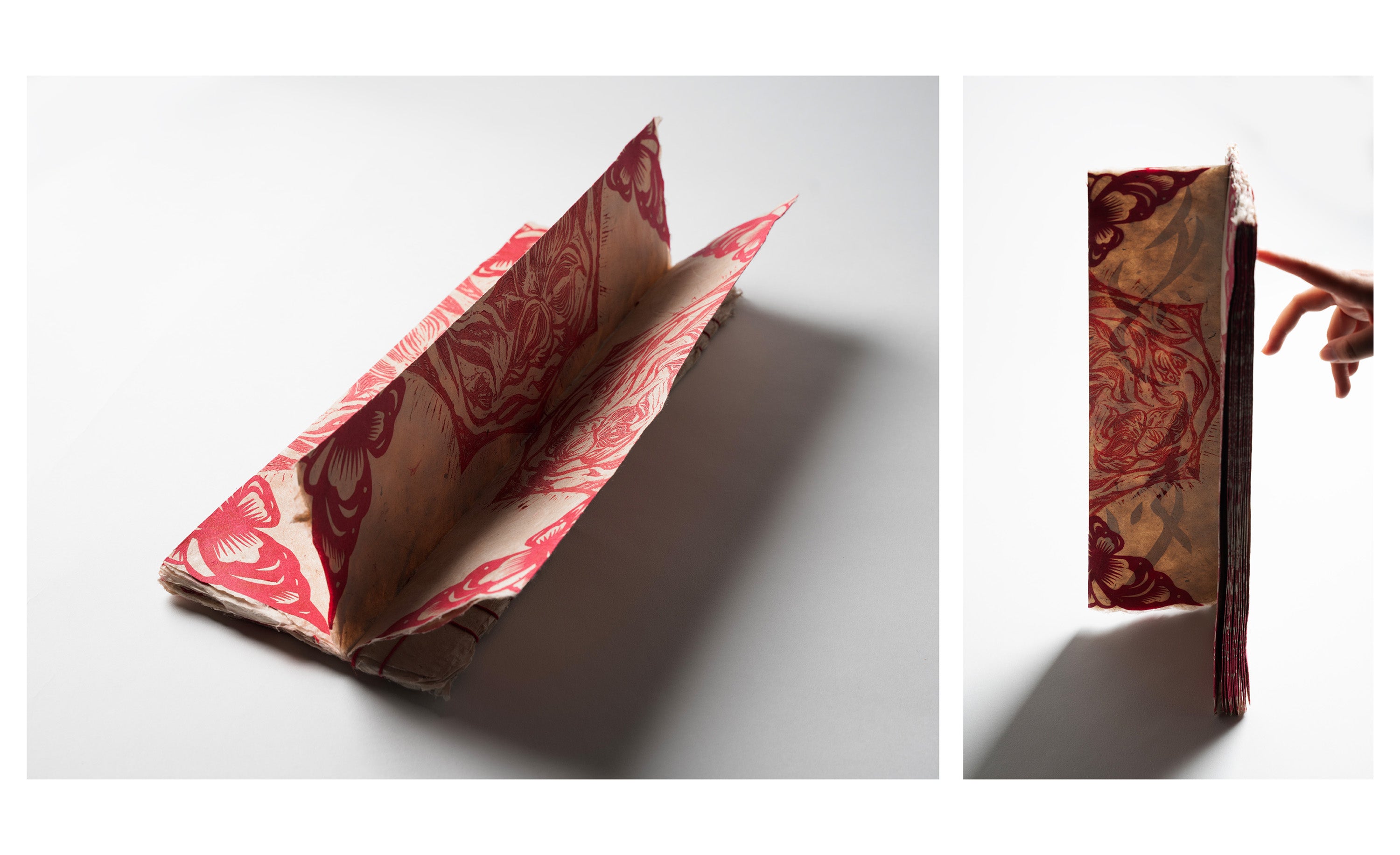 Handmade artist book with red floral prints, shown open and standing upright with a hand turning a page.