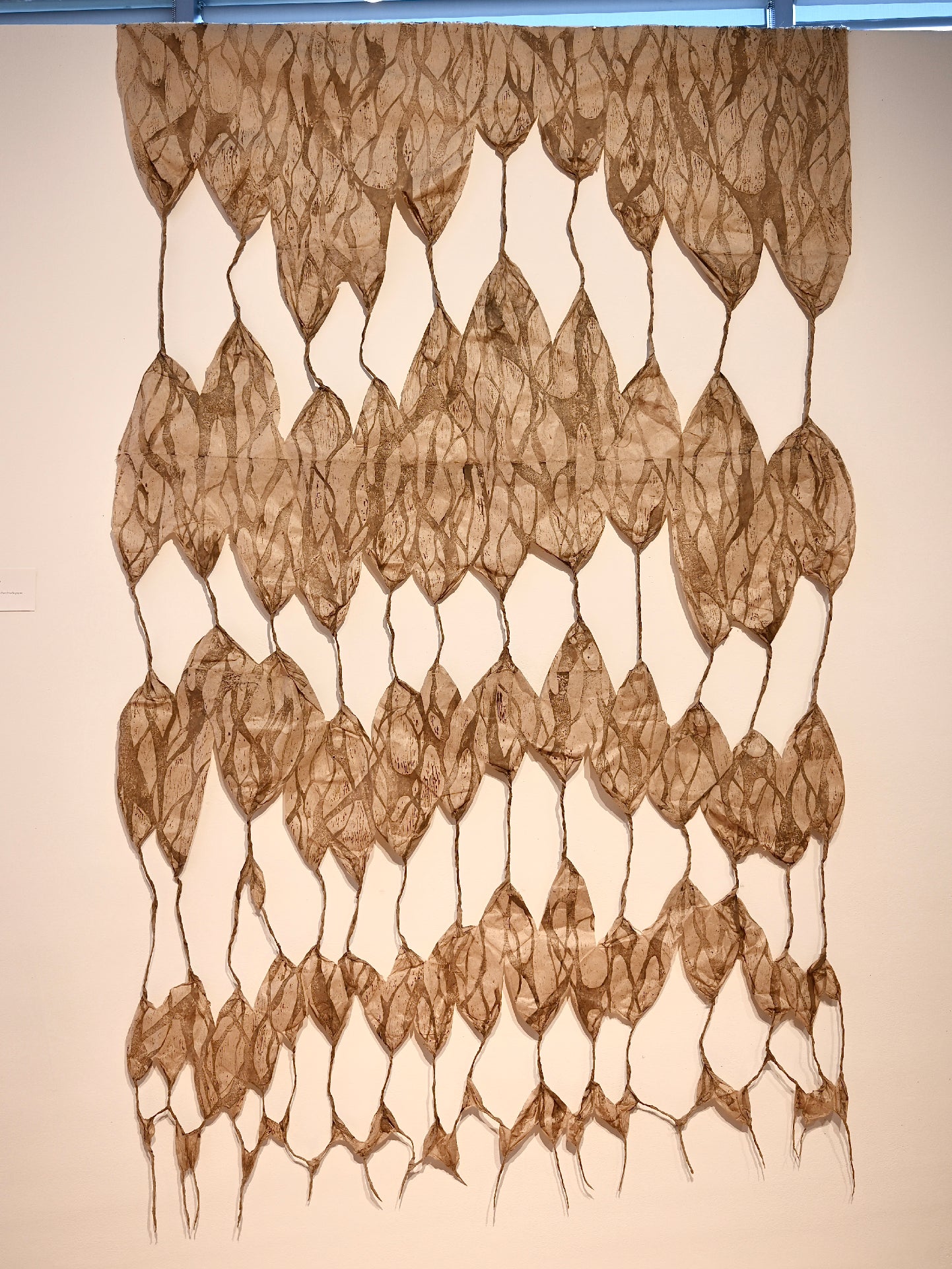 Layered handmade paper print with web-like forms and mycelium patterns connected by twisted paper strands.