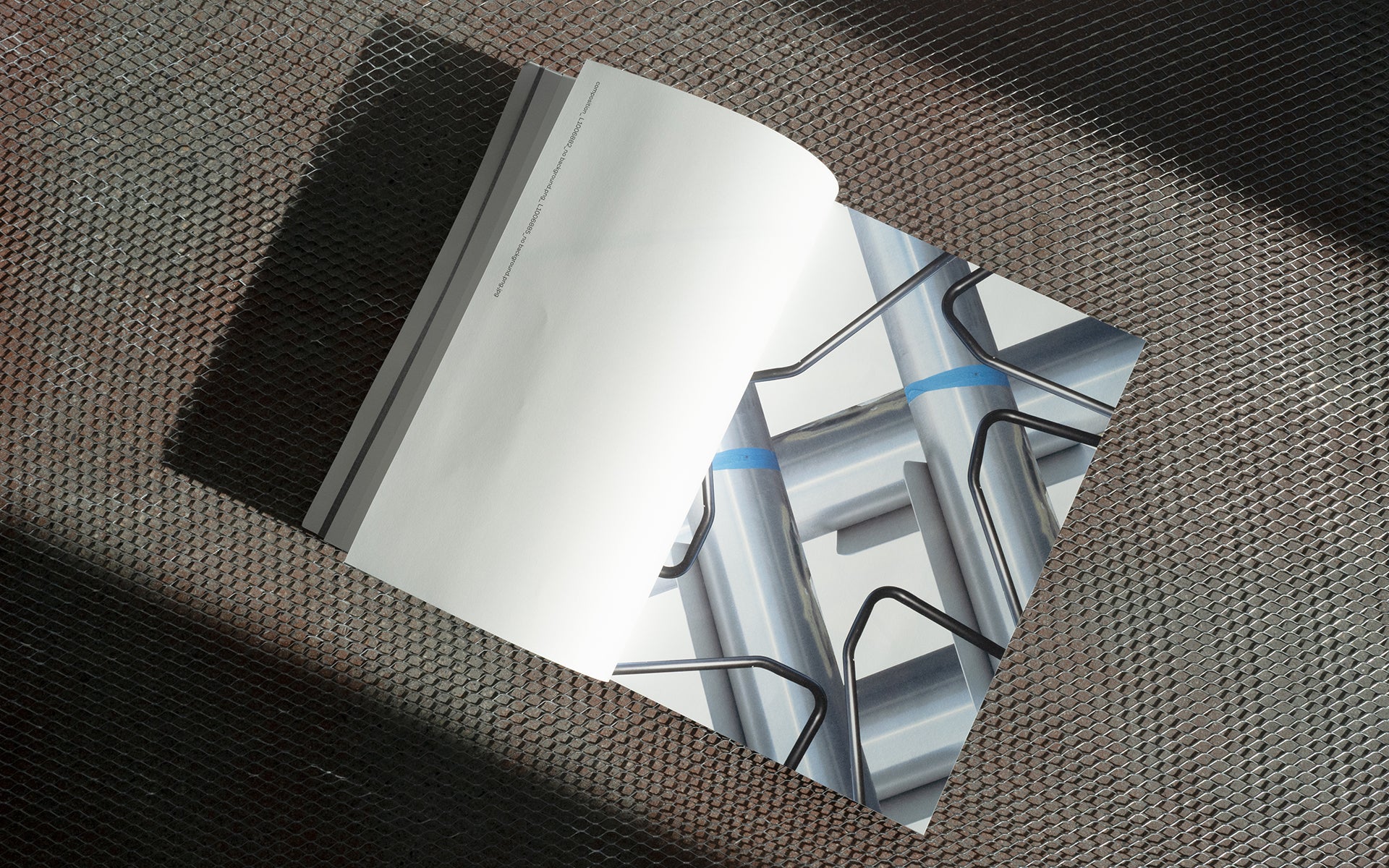 An open magazine spread laid on an expanded metal mesh surface in raking light.