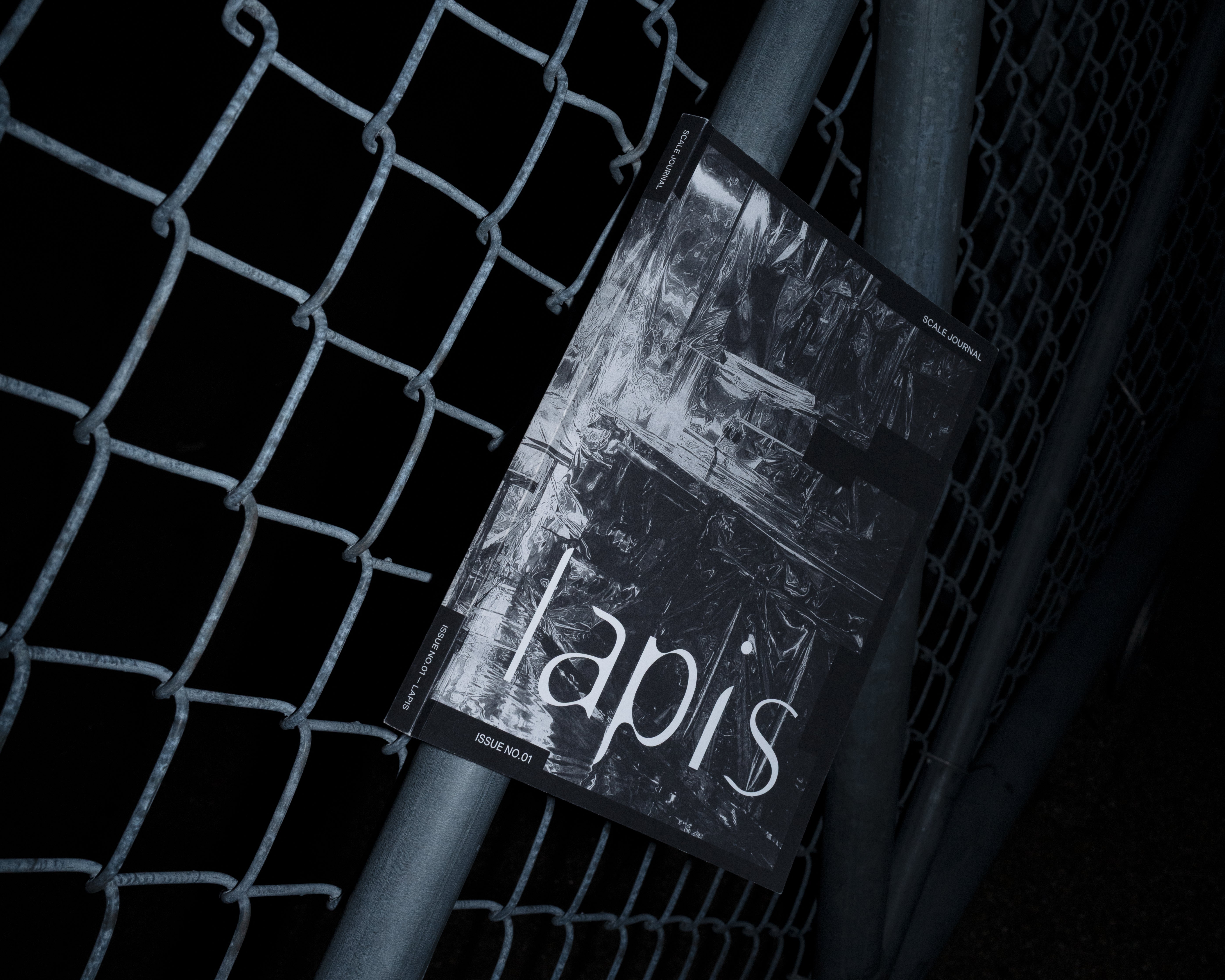 Publication copy resting against a chain-link fence.