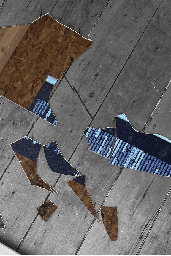 Scattered shards of a broken mirror lying on a worn wooden floor. The jagged, reflective pieces capture fragmented images of two distinct surfaces: dense white text on a dark background and the rough texture of oriented strand board (OSB).