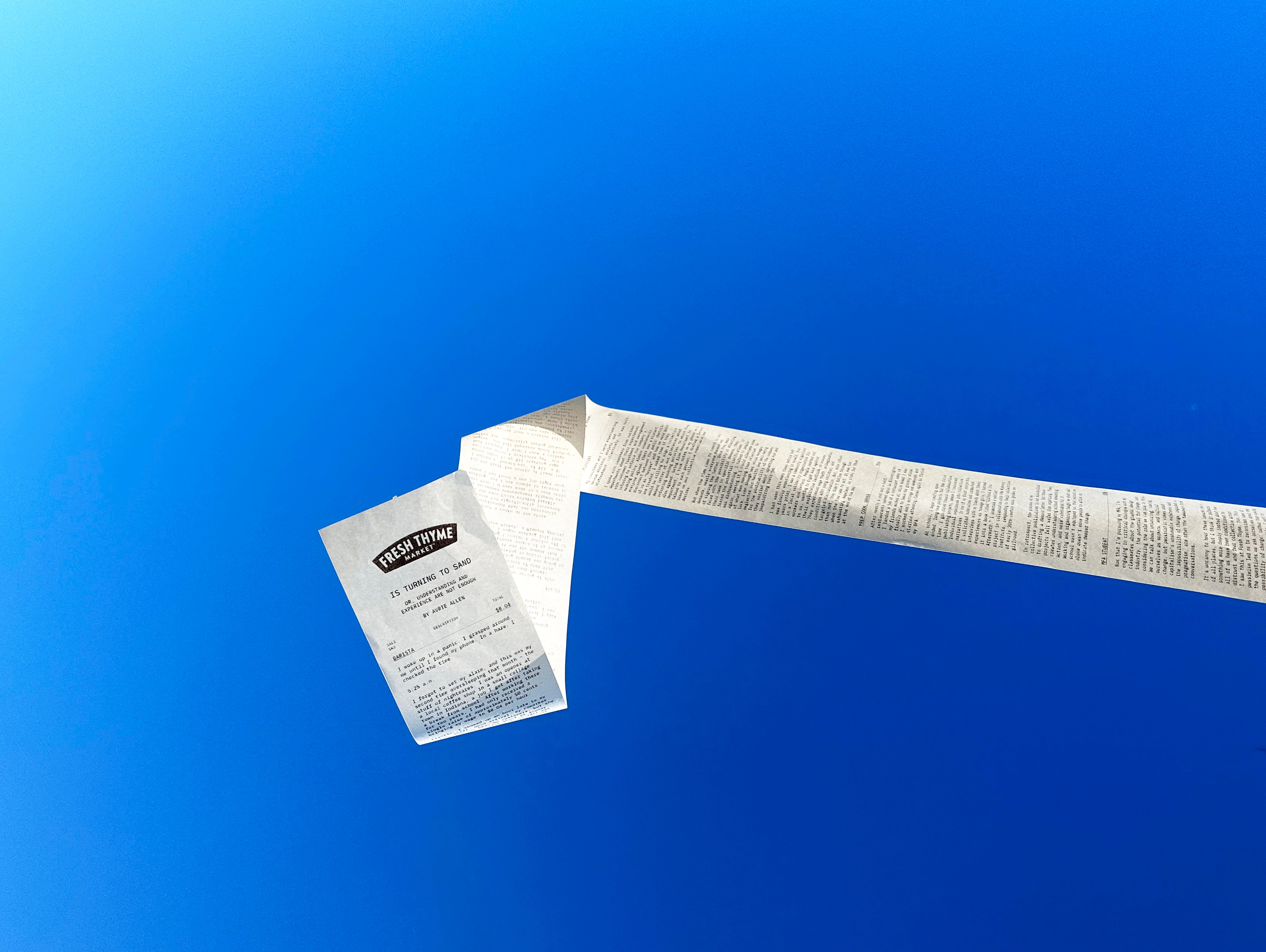 A long receipt used as the form of a publication is blowing in the wind, with blue sky in the background