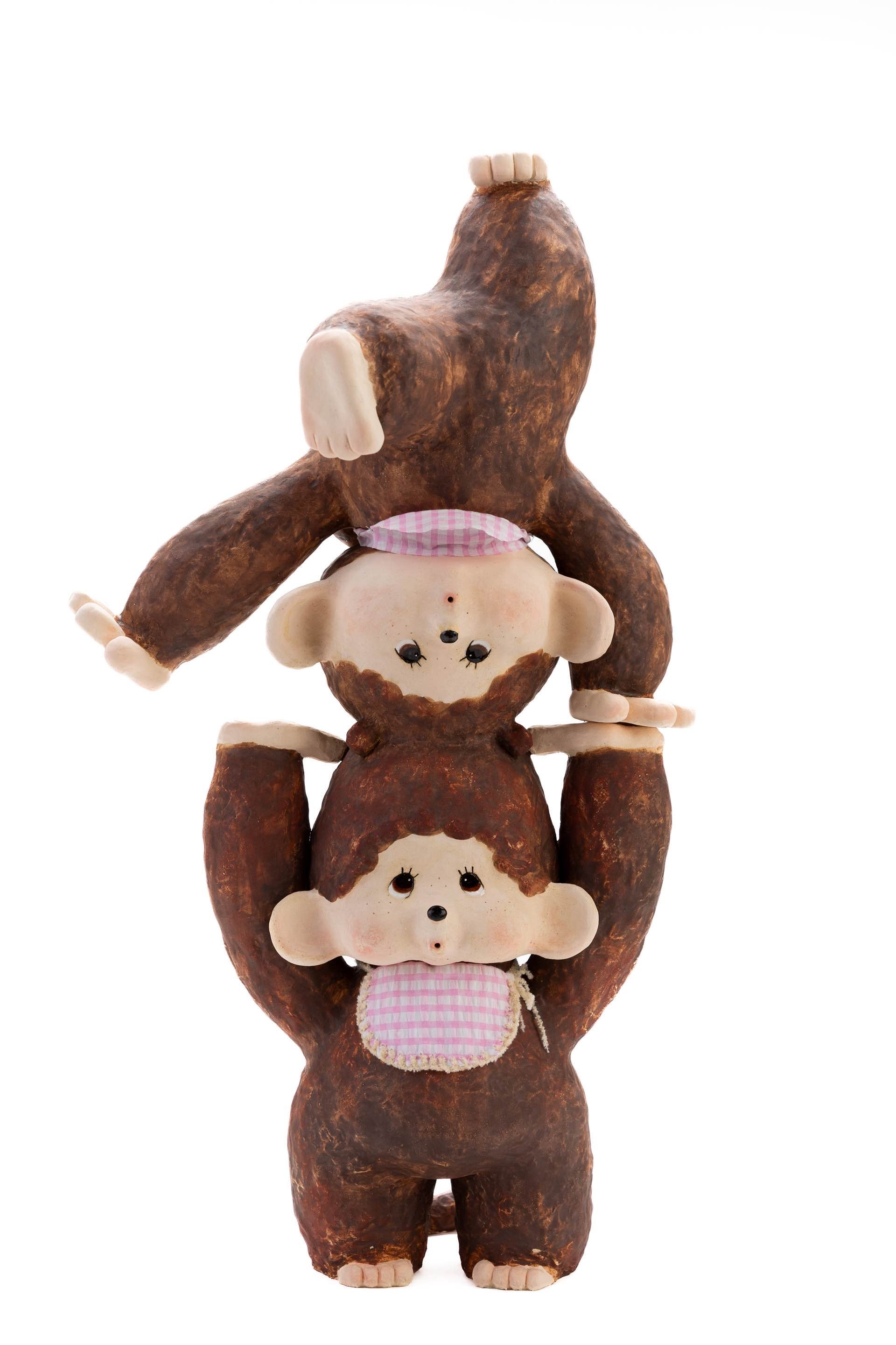 Two enlarged Monchhichi toy stacking on each other with fabrics on them. 