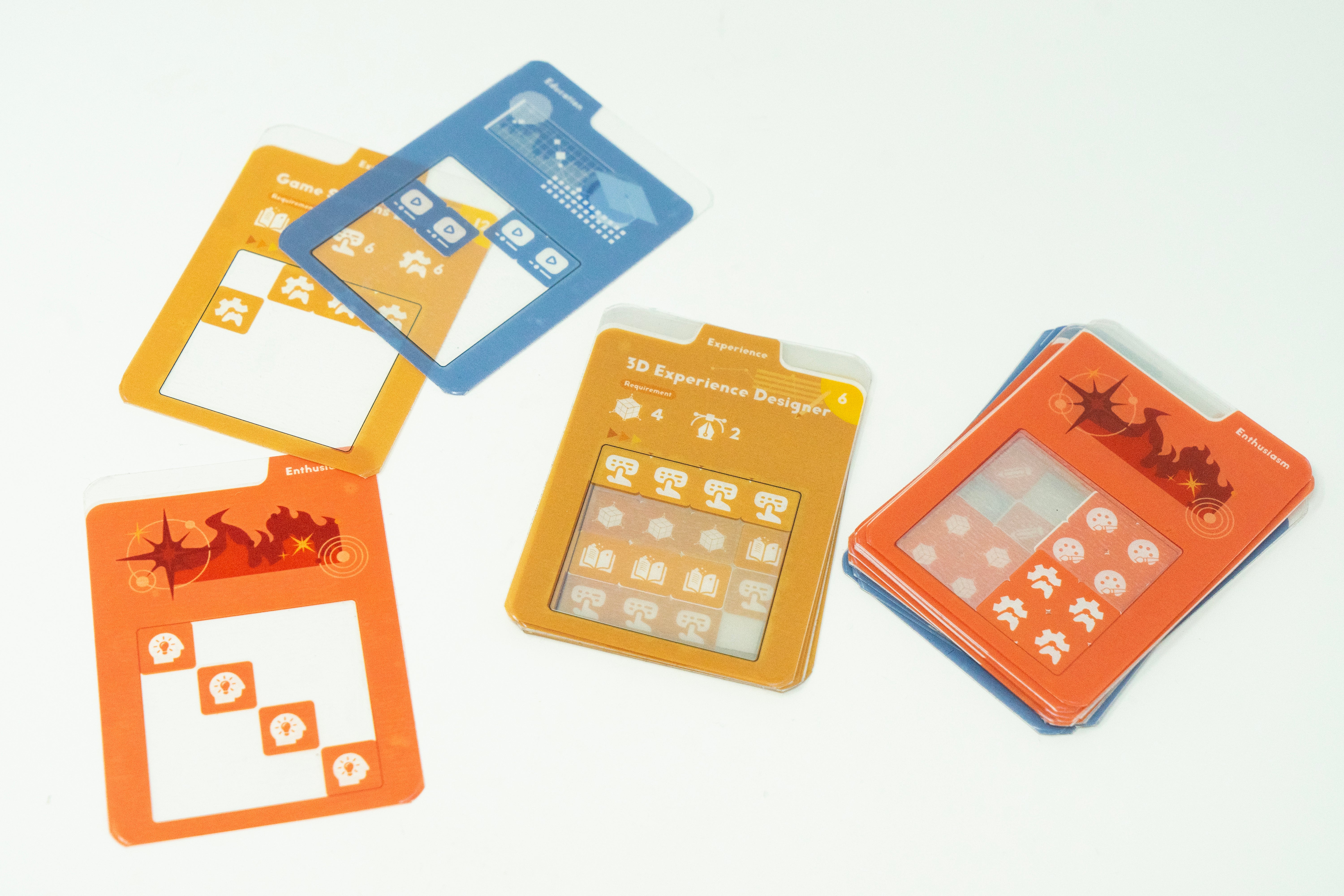 Transparent acrylic overlay cards layered over colorful role cards in a tabletop board game prototype about resume-building and persuasive communication.