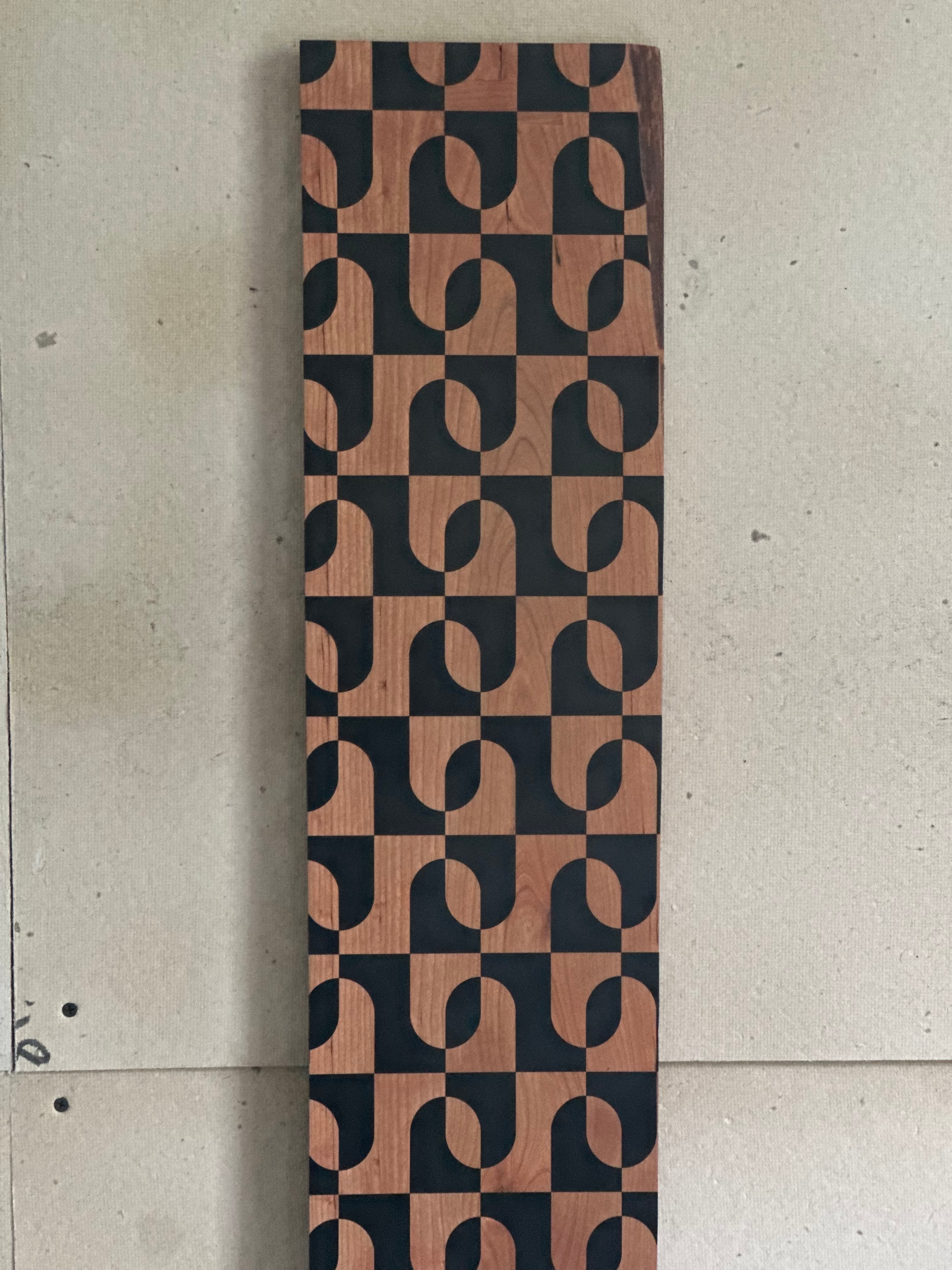 Cherry wood growth chart with a geometric pattern created through masked black vinyl mounted to the wood. 