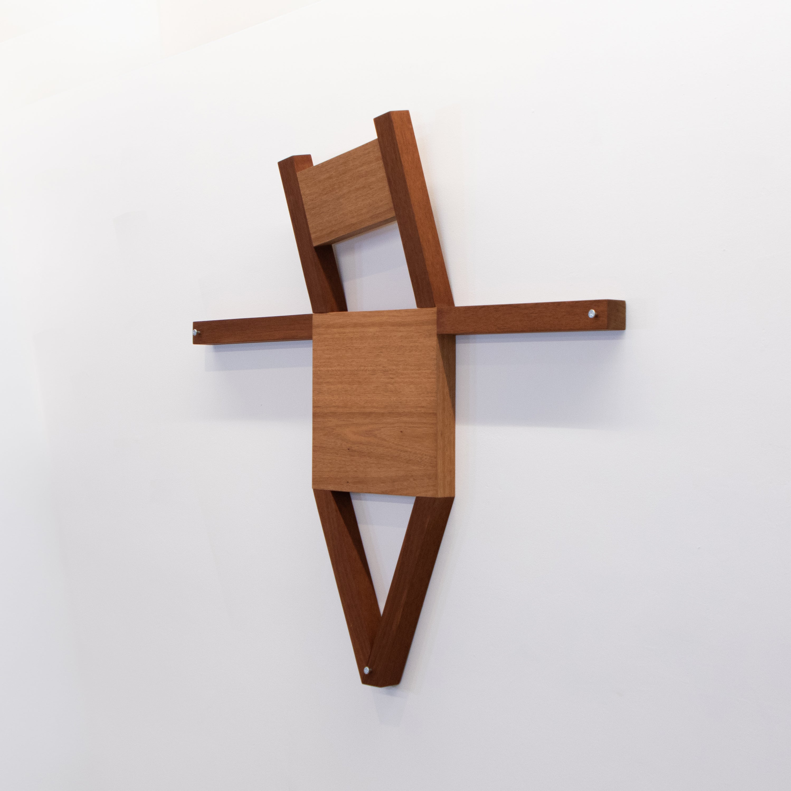 A mahogany chair transformed into a cruciform figure, combining the form of furniture with the posture of a crucified body.