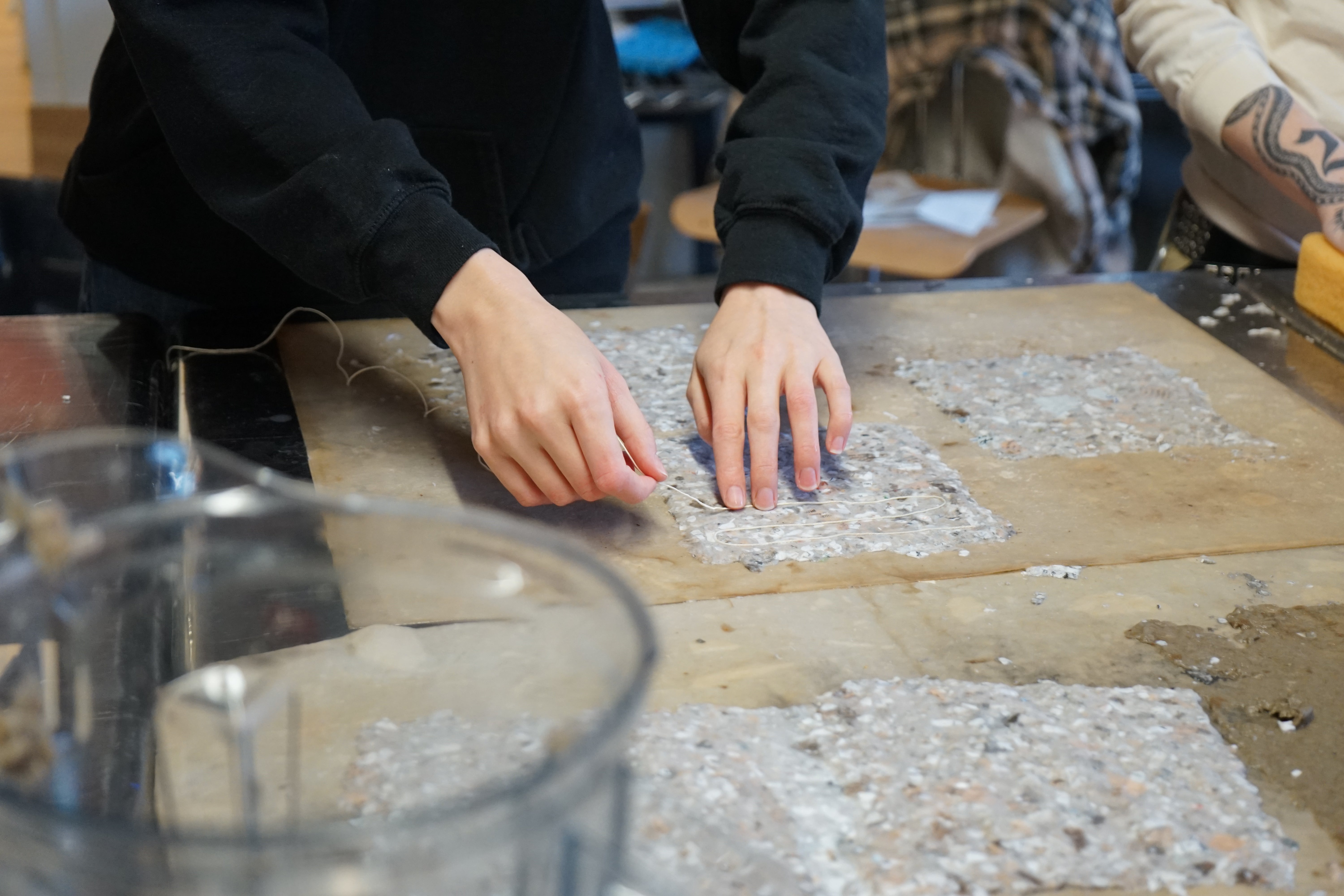 Image of student laying chord on to couched paper pulp. Set in the landscape architecture studio at Weybosset St.