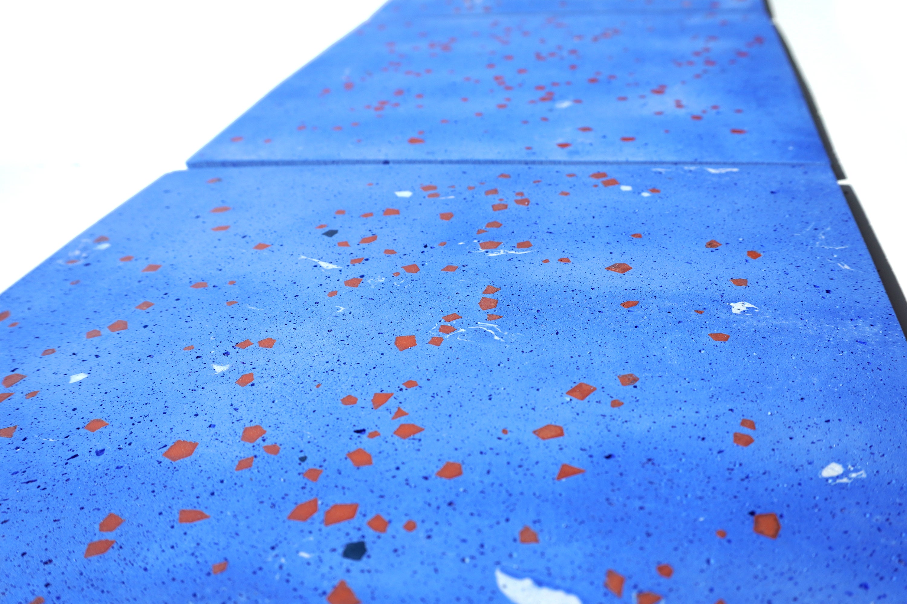 Pale blue terrazzo tiles with scattered geometric fragments seen from a low angle, receding into the distance.