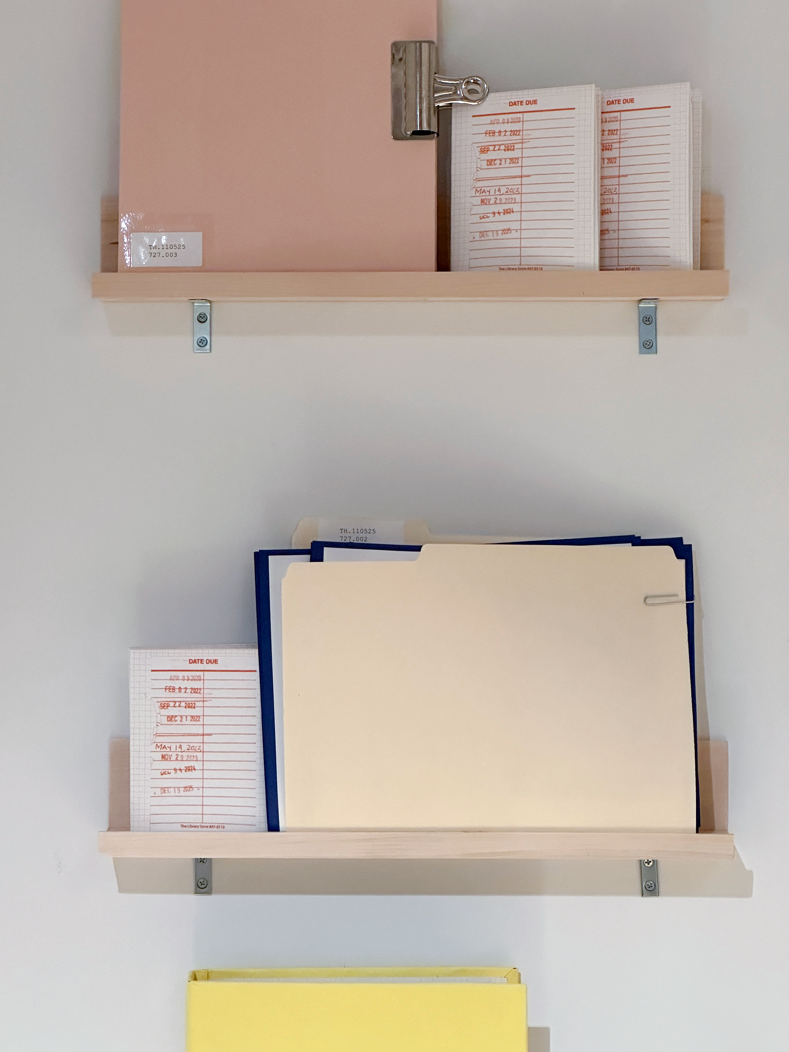 an image of two wooden shelves mounted on a wall with different colored and sized books