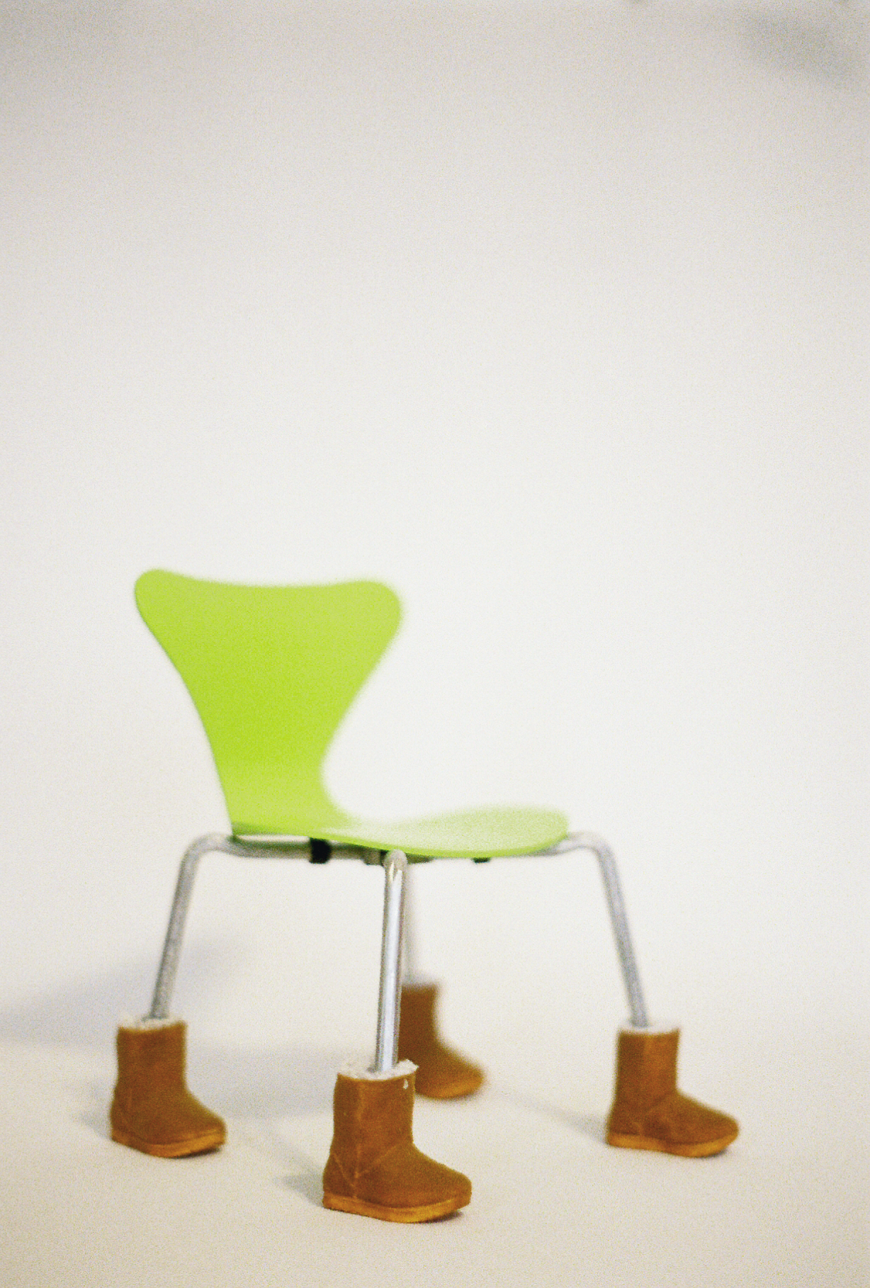 35mm film photograph of a 7" model of a neon green Series 7 chair wearing Ugg boots.
