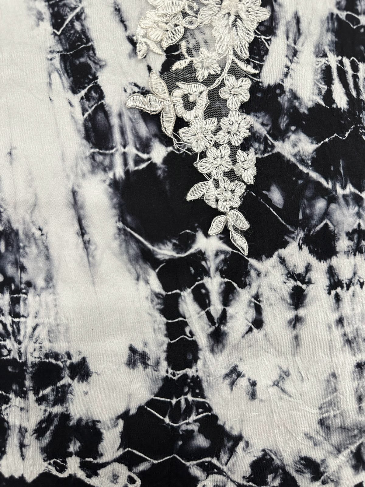Close-up of black-and-white hand-dyed silk textile with white floral embroidery appliqué over sheer mesh