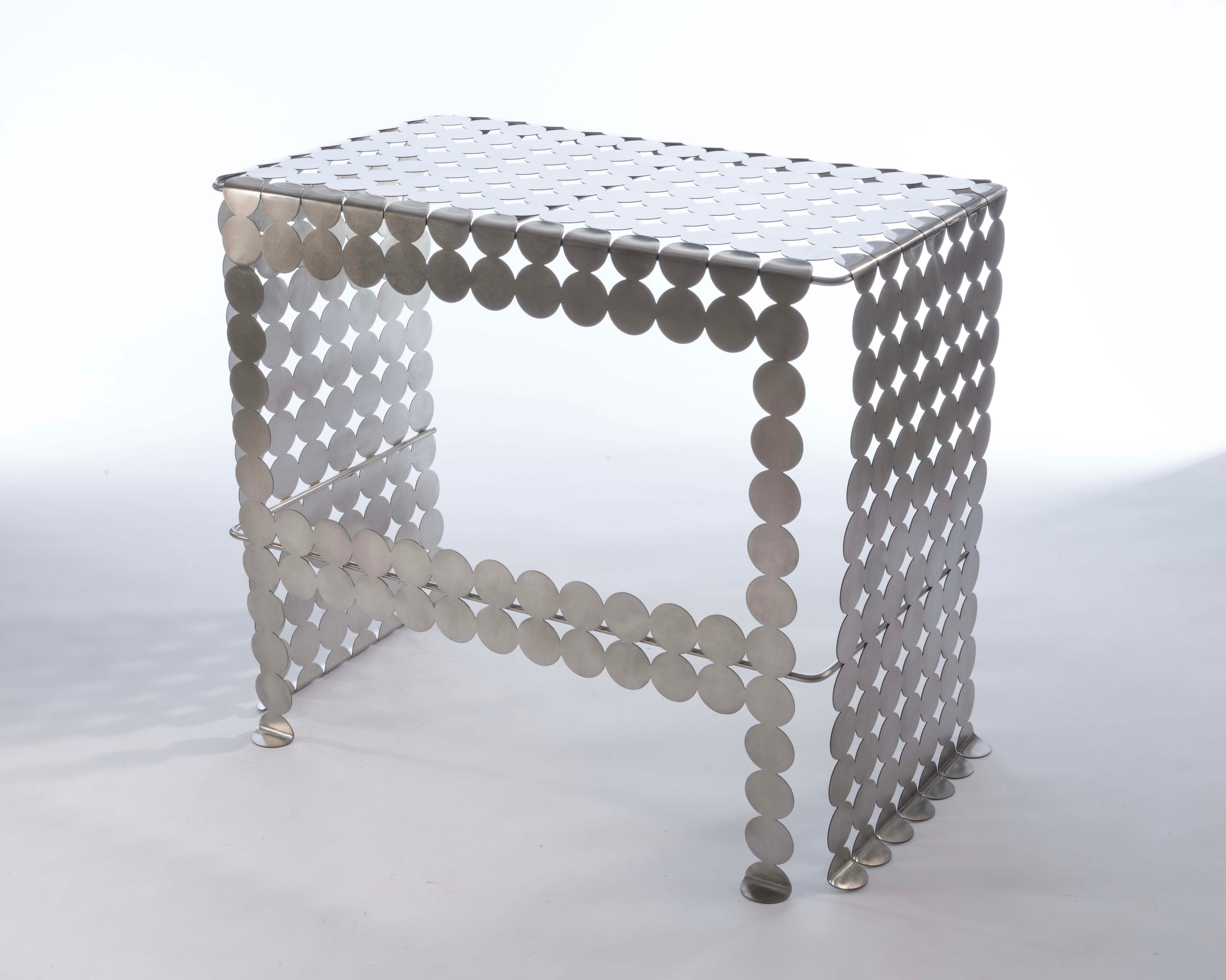 A mirror polished stainless steel vanity table with a circular, gridded pattern. 