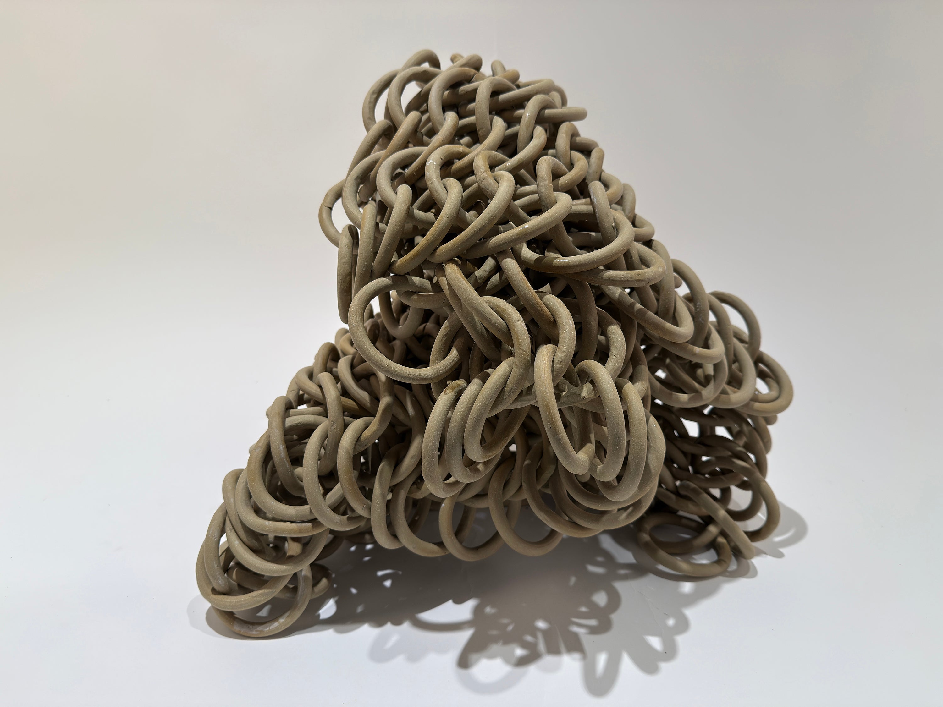 Smooth tan loops form a sheet of heavy chainmail drooping over by its own weight.