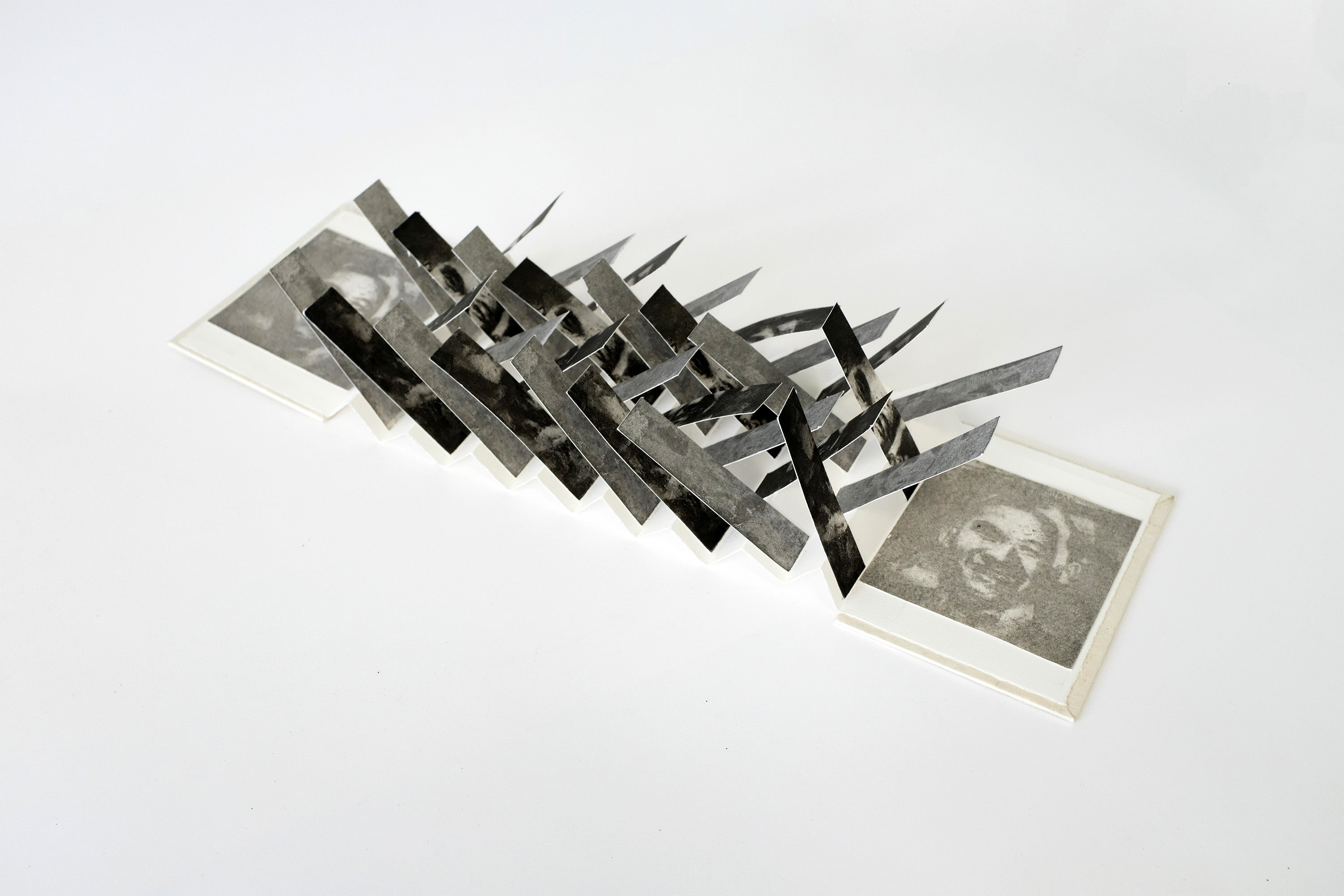 Open book with criss-crossing slips of paper. The slips display a distorted and monochrome male portrait.