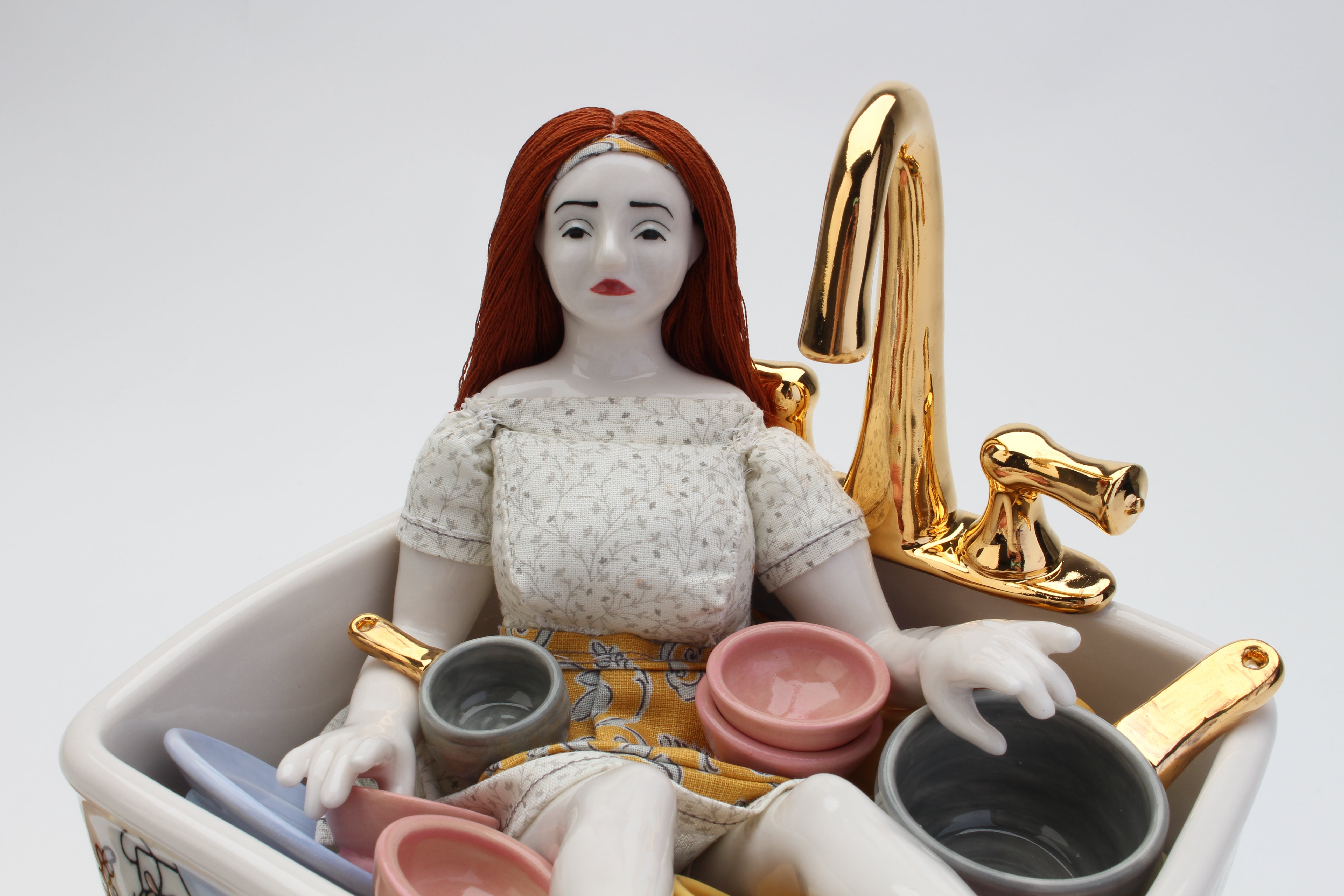 a sad doll sitting in a sink filled with colorful dishes, illustrated with a dining room scene and floral decoration