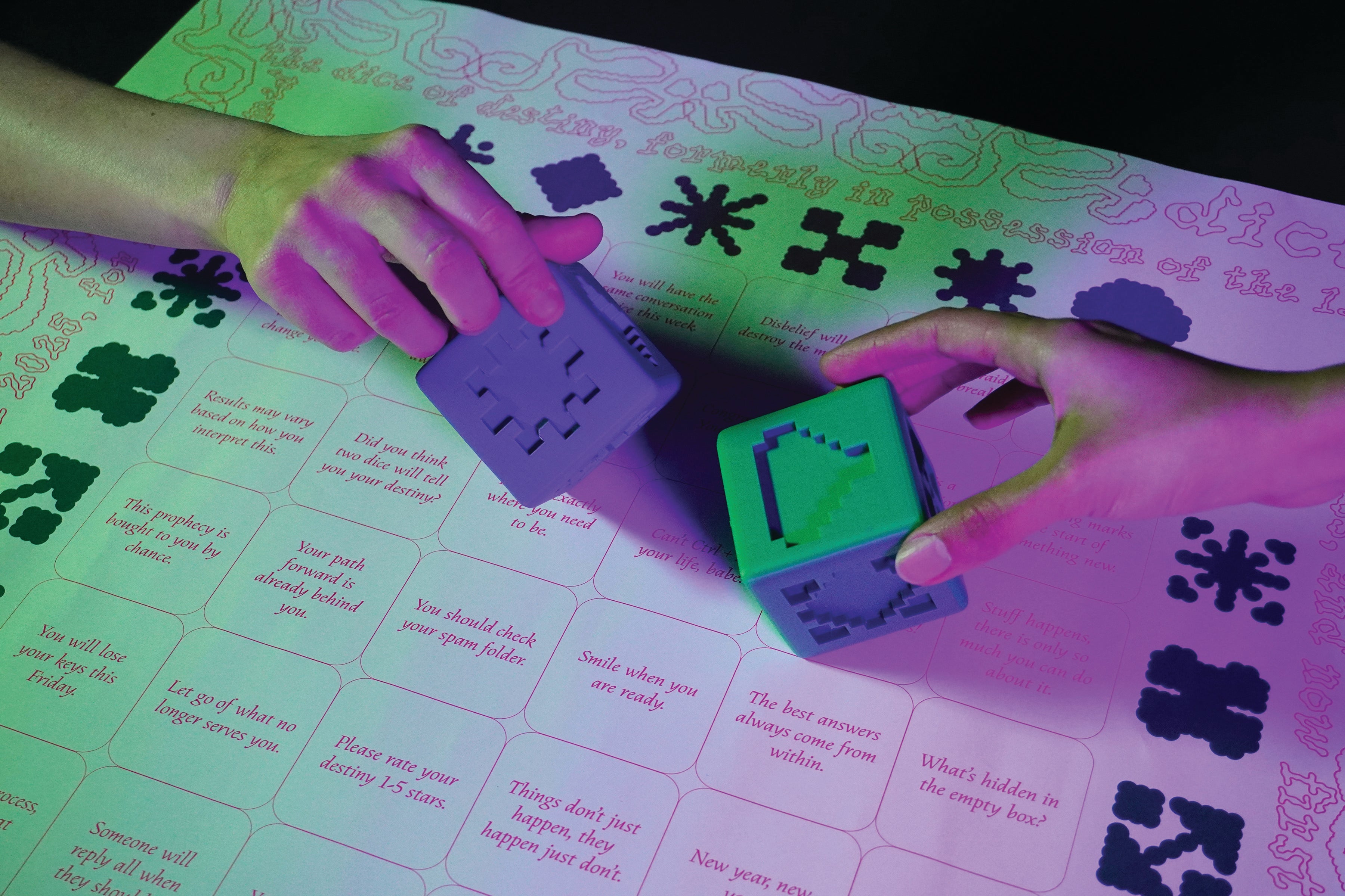Two glowing dice with abstract symbols rest on a fortune-telling chart, their faces illuminated in vibrant green, blue, and purple against text containing 36 mystical fortunes exploring chance and meaning-making.
