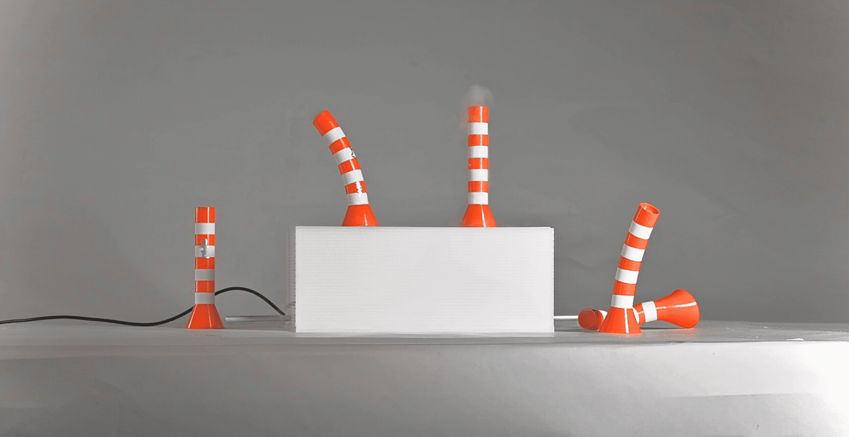 Video of orange-and-white steam stacks on a white box platform. Steam is generated inside the box, and is released through the steam stacks above.