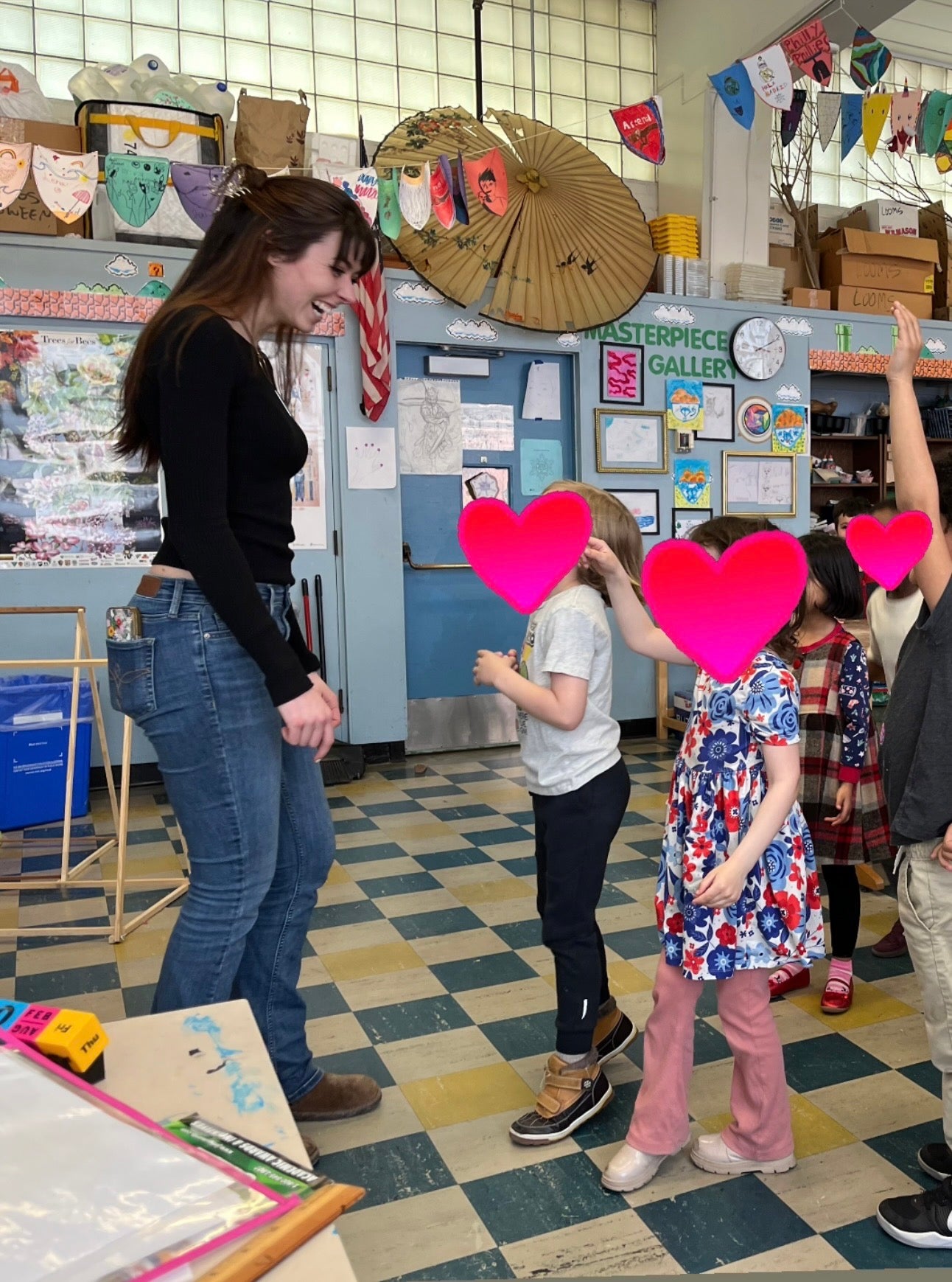 students rush up to a teacher at the front of the classroom jumping up and down with their hands raised