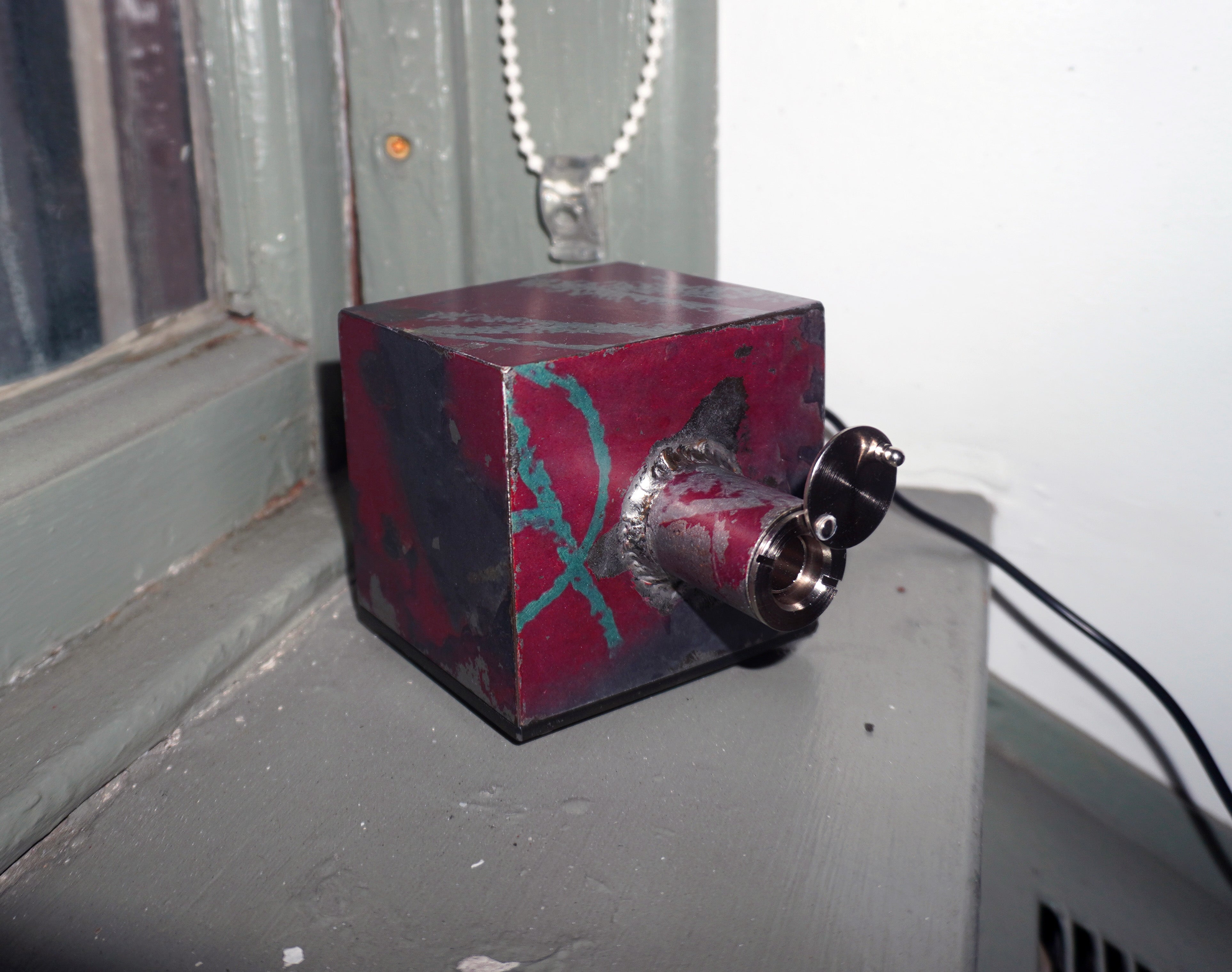 An alarm clock locked inside of a small metal box, that can only be viewed through a peephole.