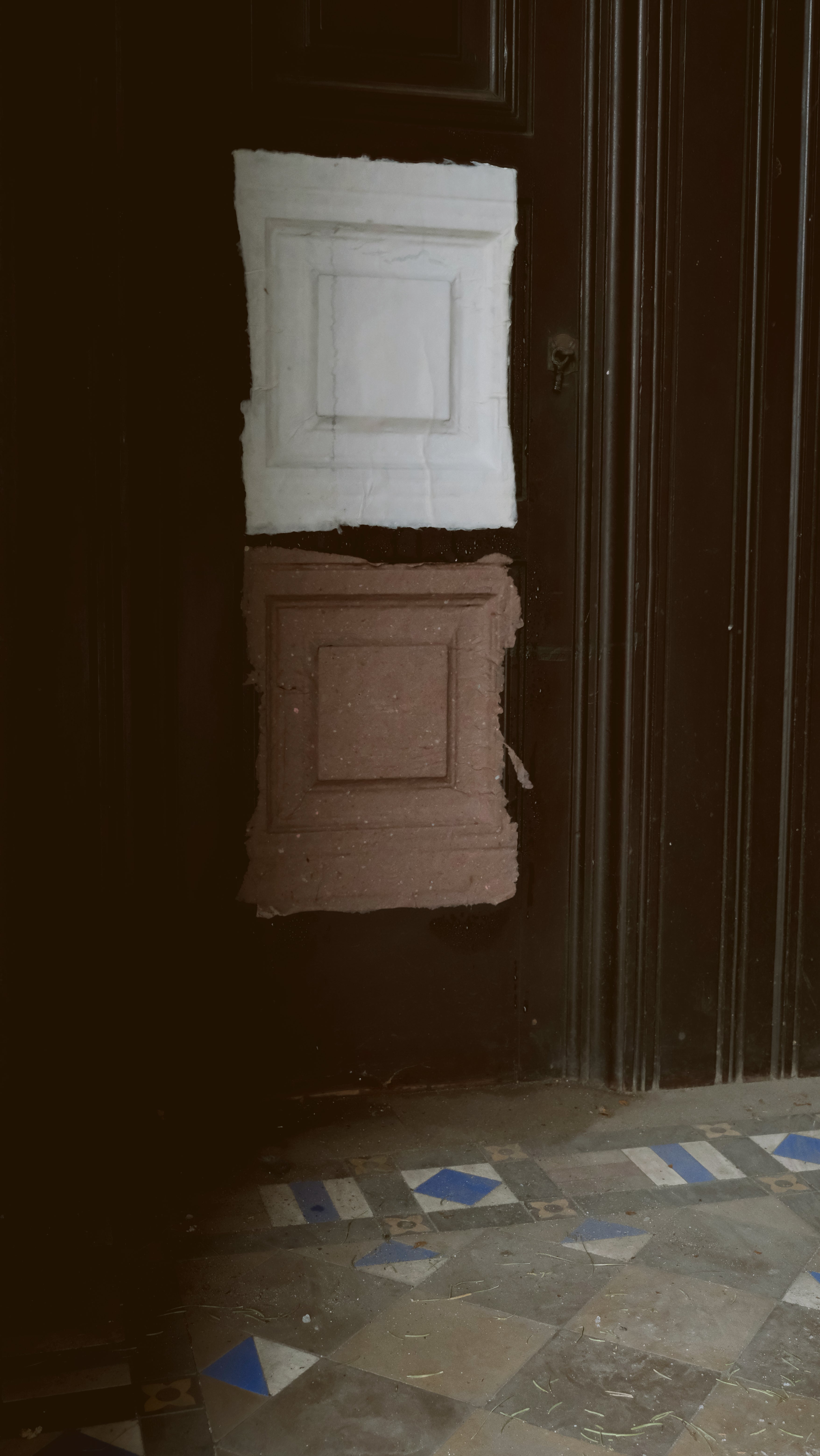 A sheet of wet handmade paper pressed flat against an ornate interior wall, capturing the surface texture and architectural detail of a historic Providence vestibule.