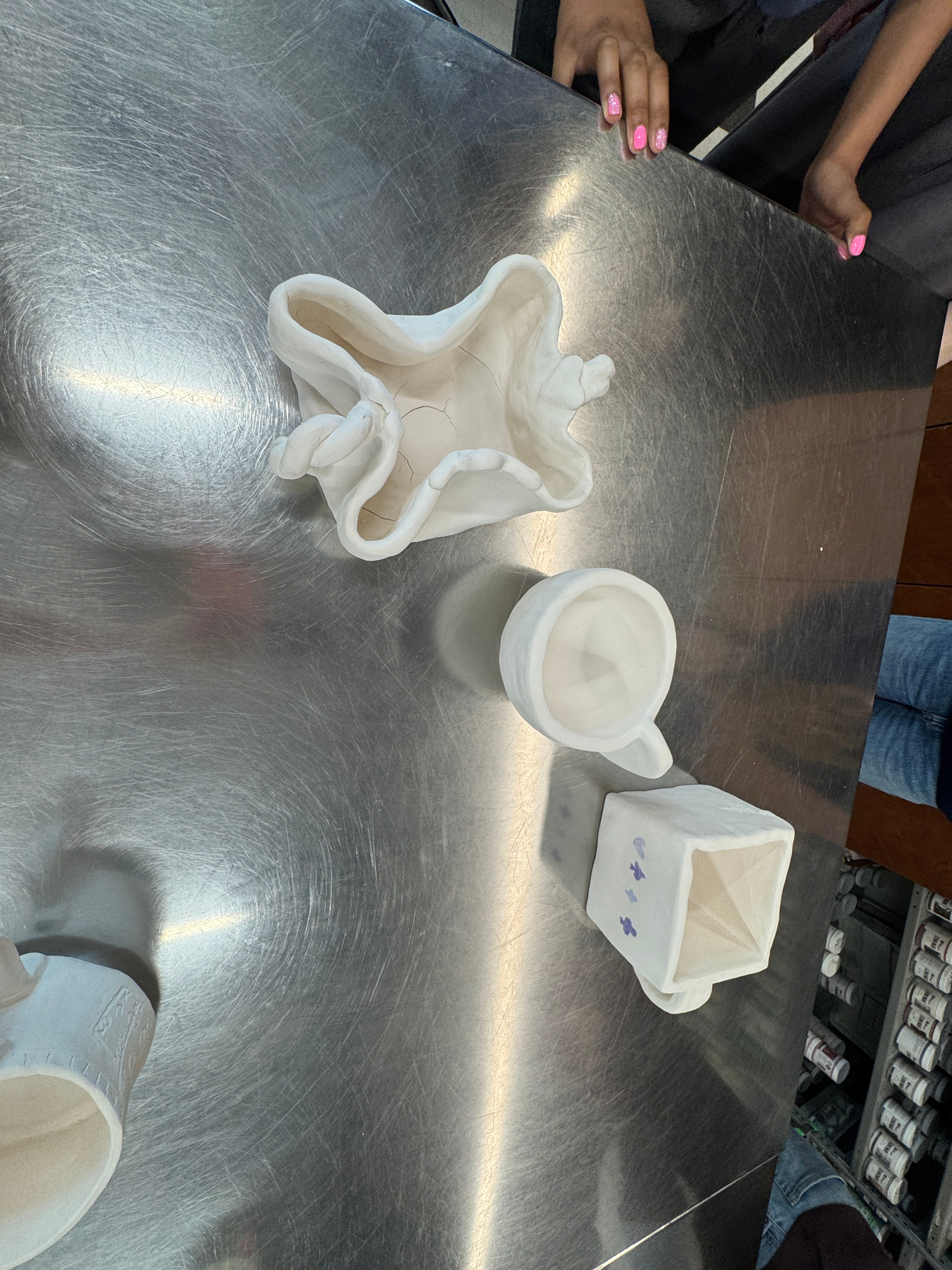 Students out of frame contemplate glazing and color decisions for their tea cups