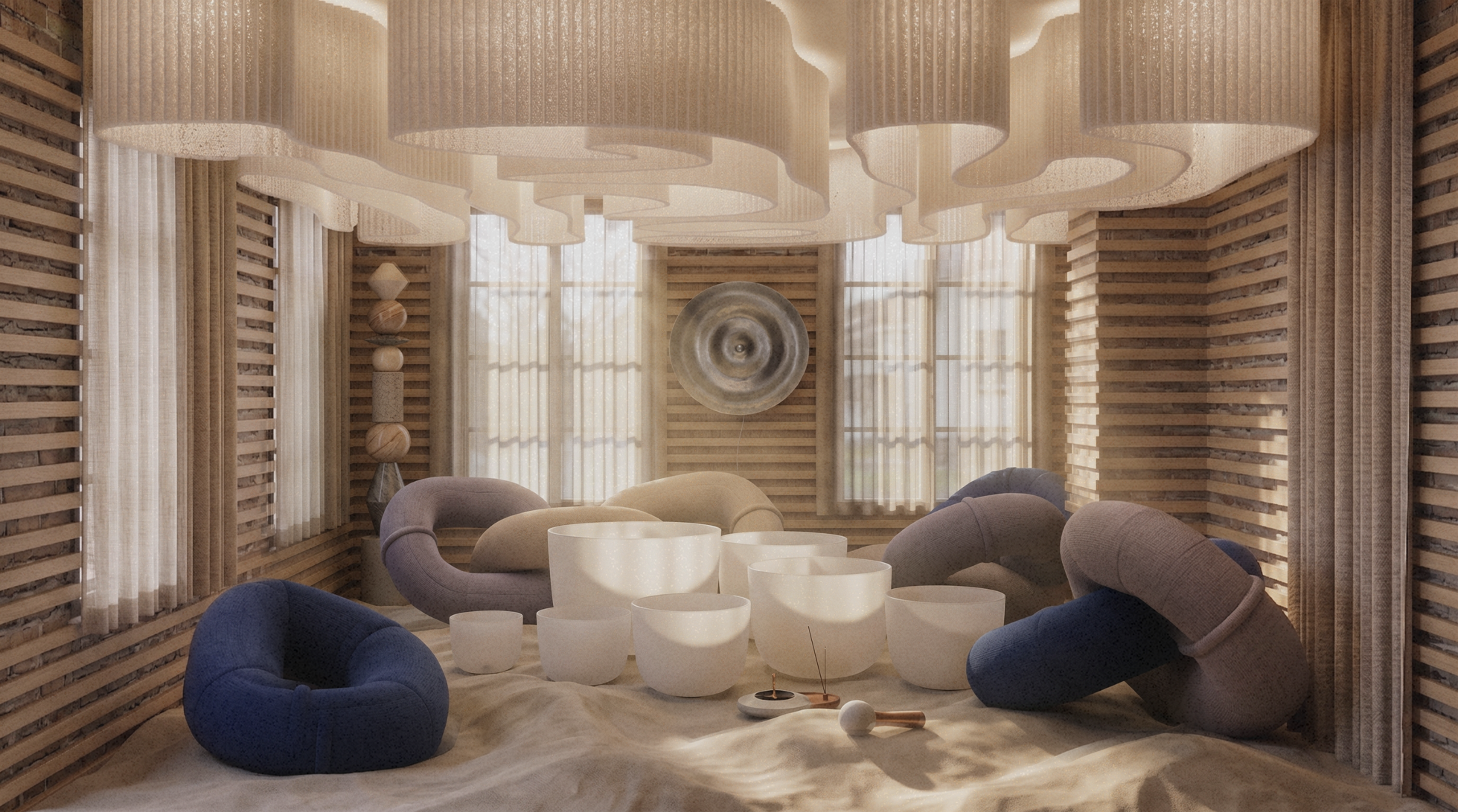 A rolling sand floor fills a meditative space lined with slatted wooden walls. Below a billowing, fabric ceiling, white crystal singing bowls sit amongst plush, ring-shaped floor sofas in blue and beige.