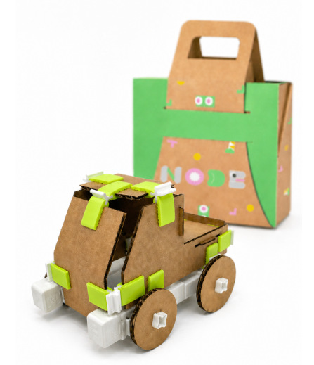 Cardboard truck assembled with green and white connectors, with a NODE-branded box blurred in the background.